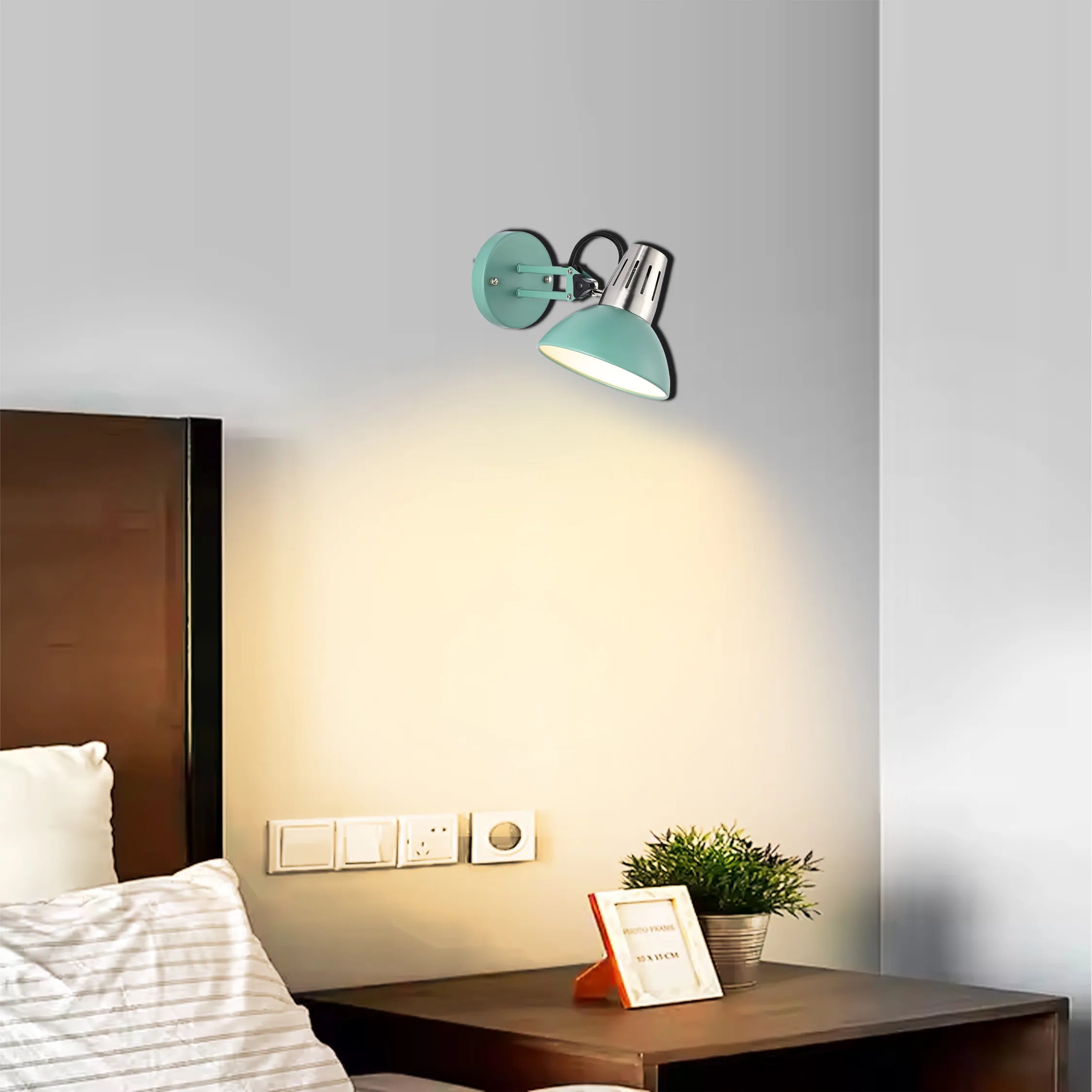 A stylish turquoise wall lamp illuminates a bedside table, casting a warm glow in a contemporary bedroom setting.