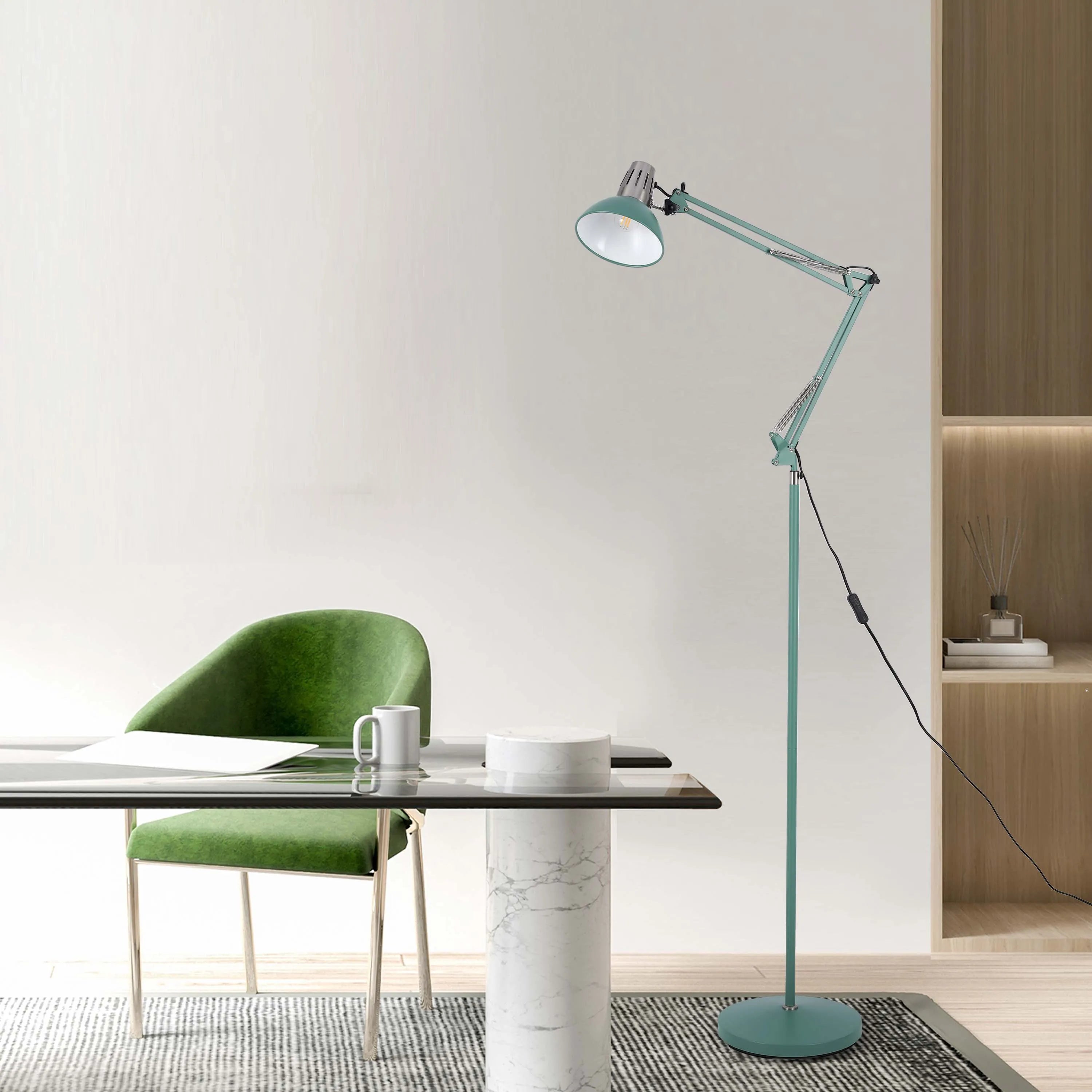 An adjustable light teal floor lamp illuminates this workspace. A modern design with a round base sits next to a table and green chair.