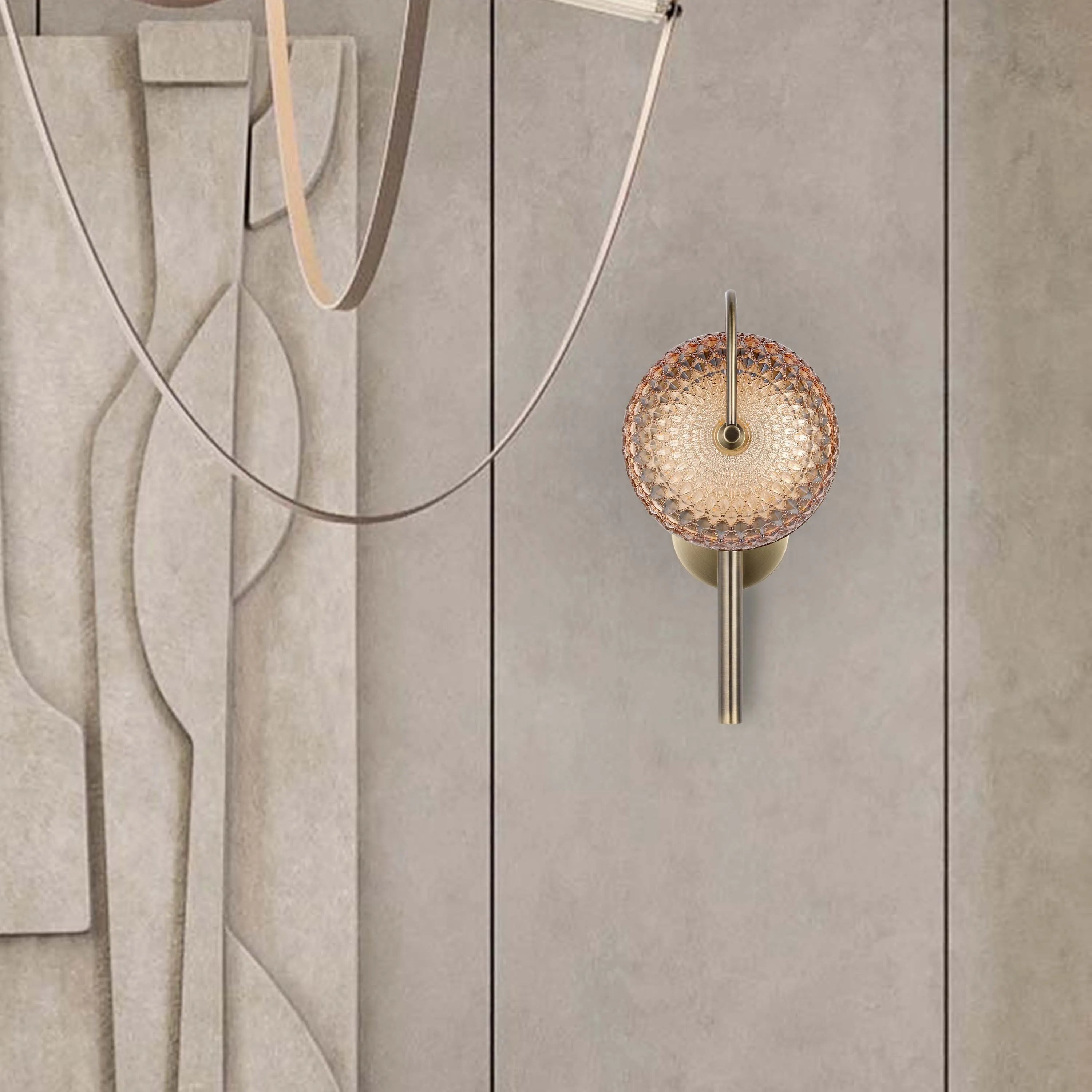 An ornate wall lamp, featuring an amber patterned diffuser and a brass-coloured mount.