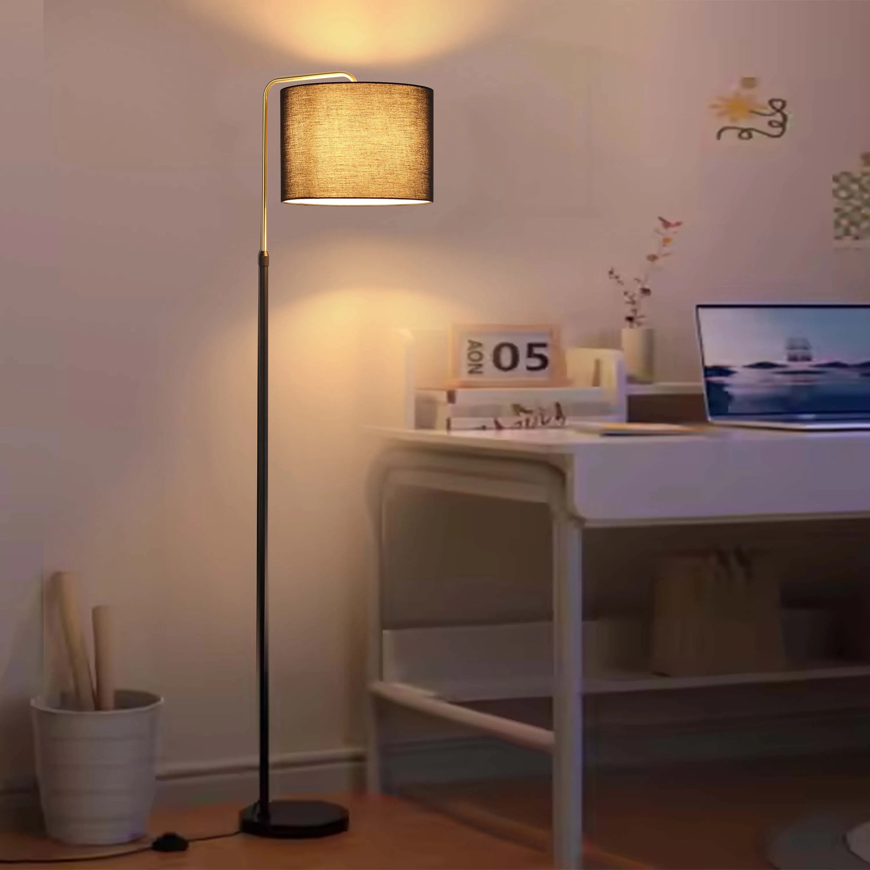 Lit floor lamp with a dark, linen drum shade casts a warm glow in a cosy interior. Ideal for creating a relaxed atmosphere.