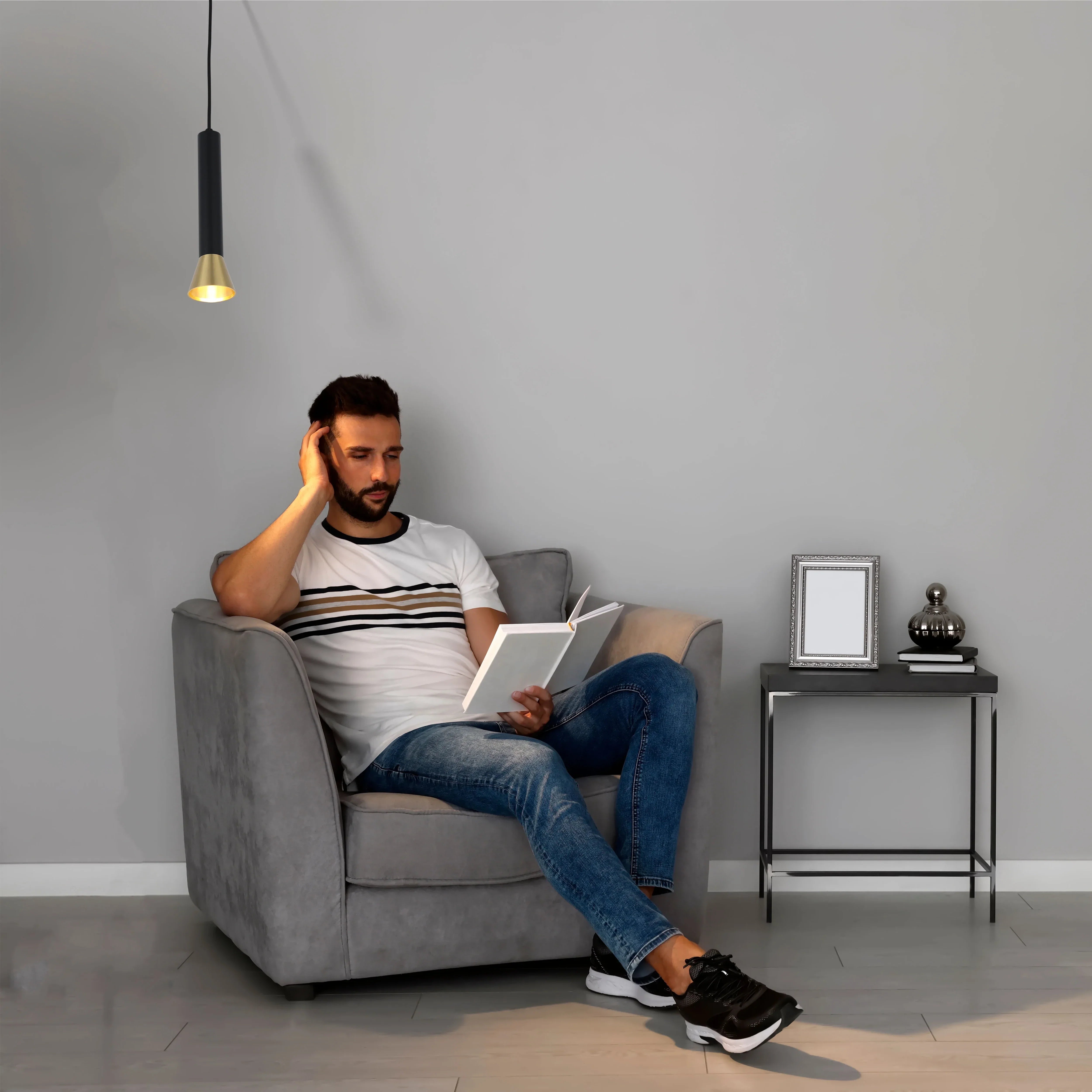 Contemporary pendant light with a black and gold finish, providing a warm, focused downlight in a neutral setting.