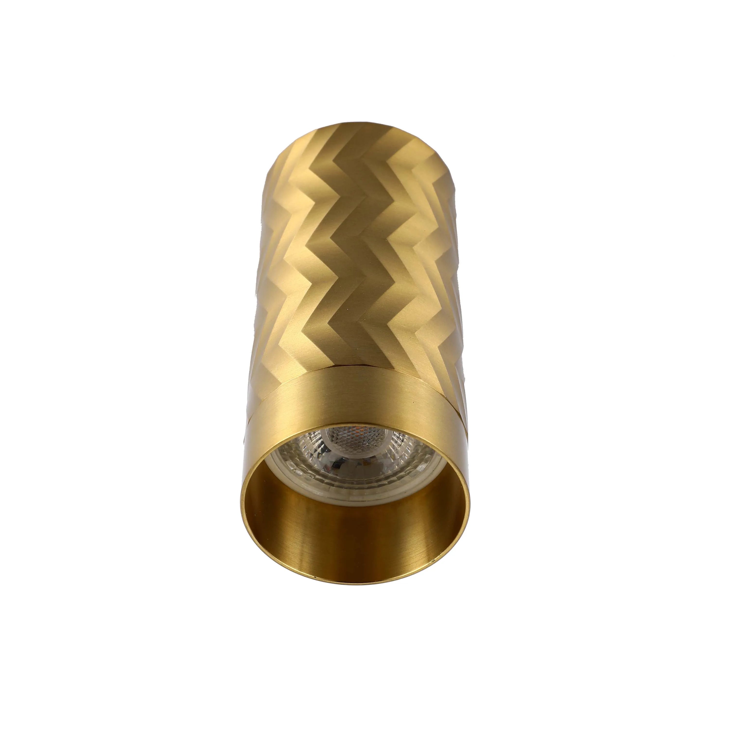 A brushed gold wall light with a cylindrical shape and a geometric, zigzag design.