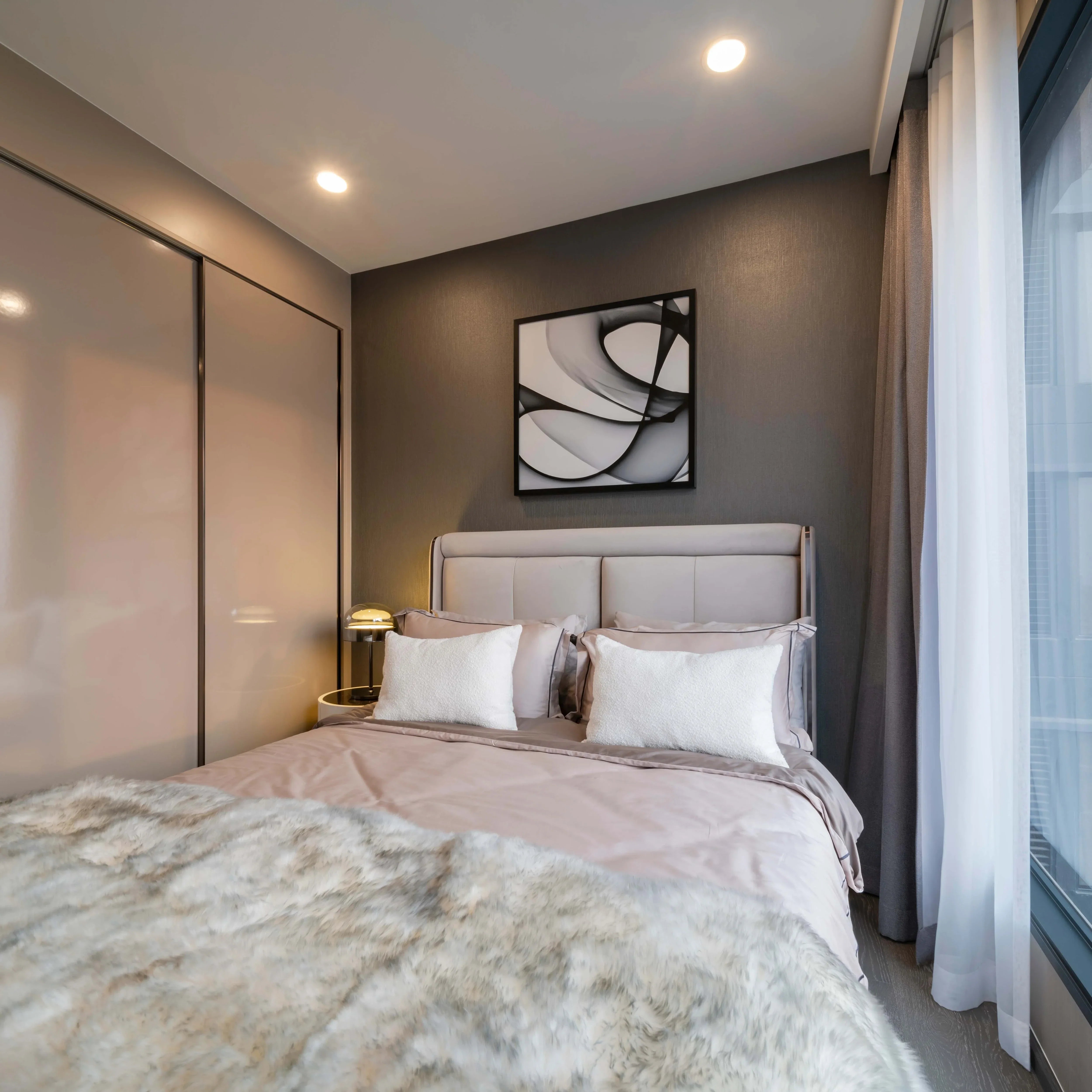 Bedroom with recessed ceiling lights illuminating the scene, complemented by a bedside table lamp for a warm, inviting ambience.