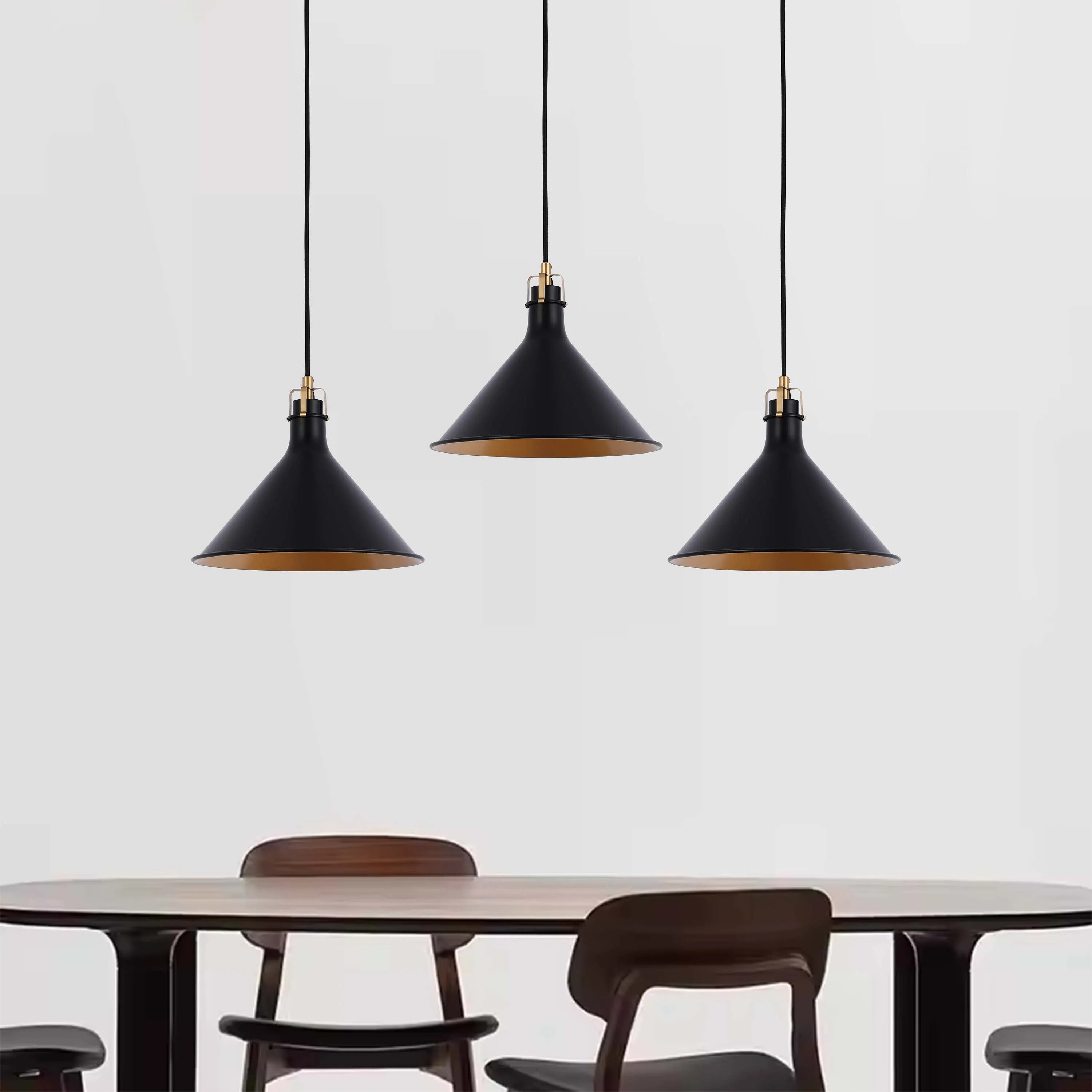 Three black cone pendant lights with gold interiors hang over a dining table, providing stylish illumination and ambiance.