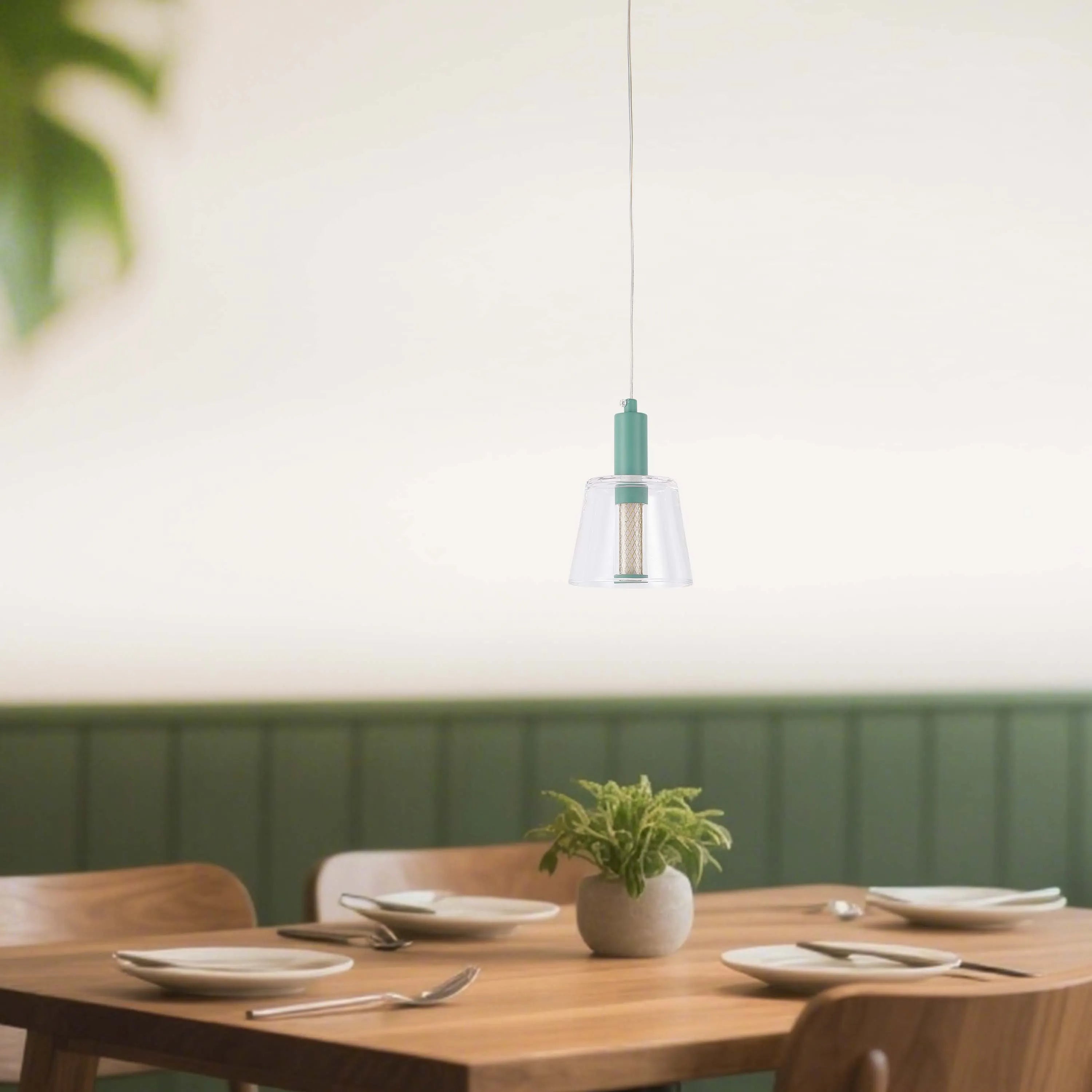 A modern, translucent pendant light with a teal accent, hanging over a set dining table, providing a soft, stylish illumination.