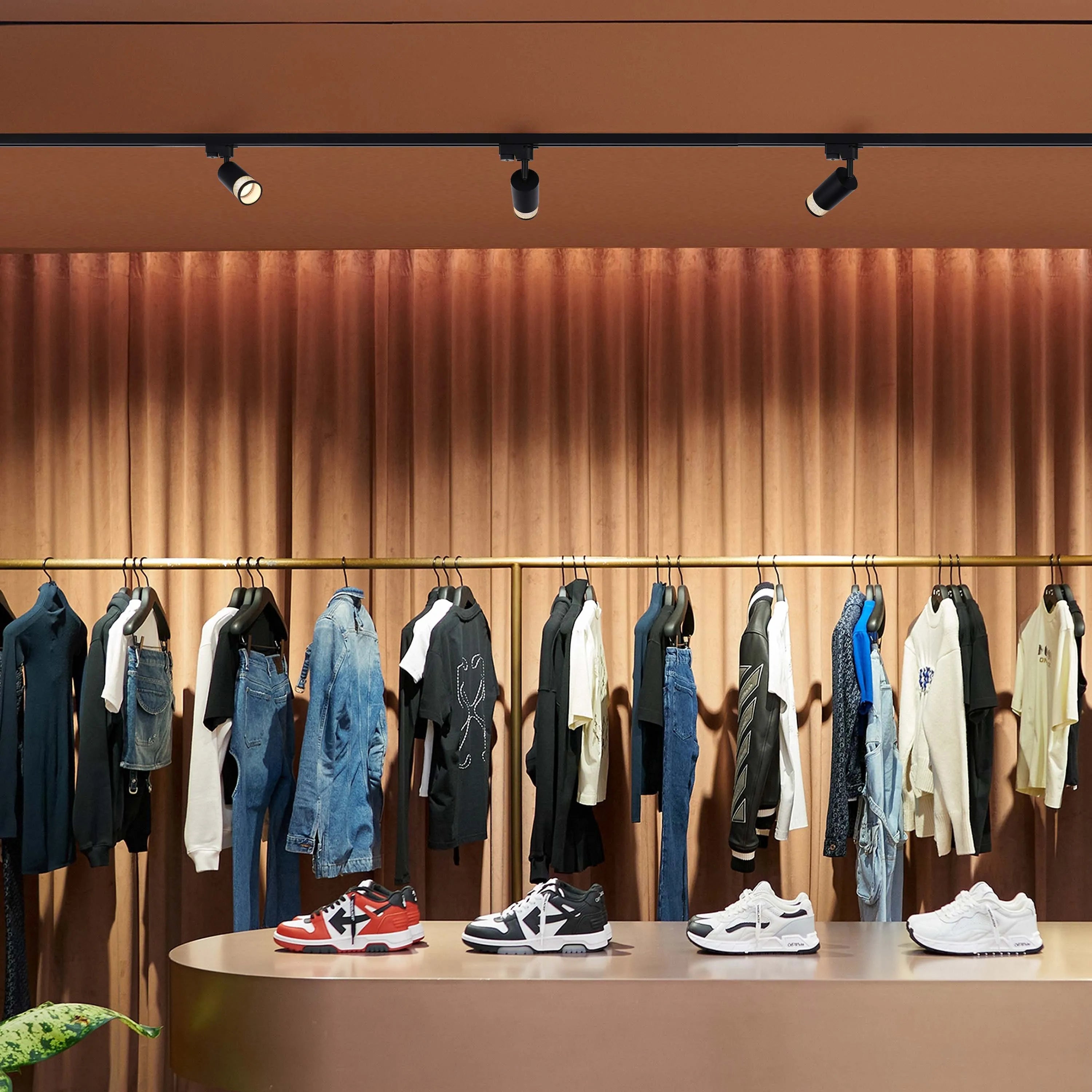 Track lighting illuminates a clothes rack. The sleek, directional spotlights provide focused and adjustable illumination for a modern look.
