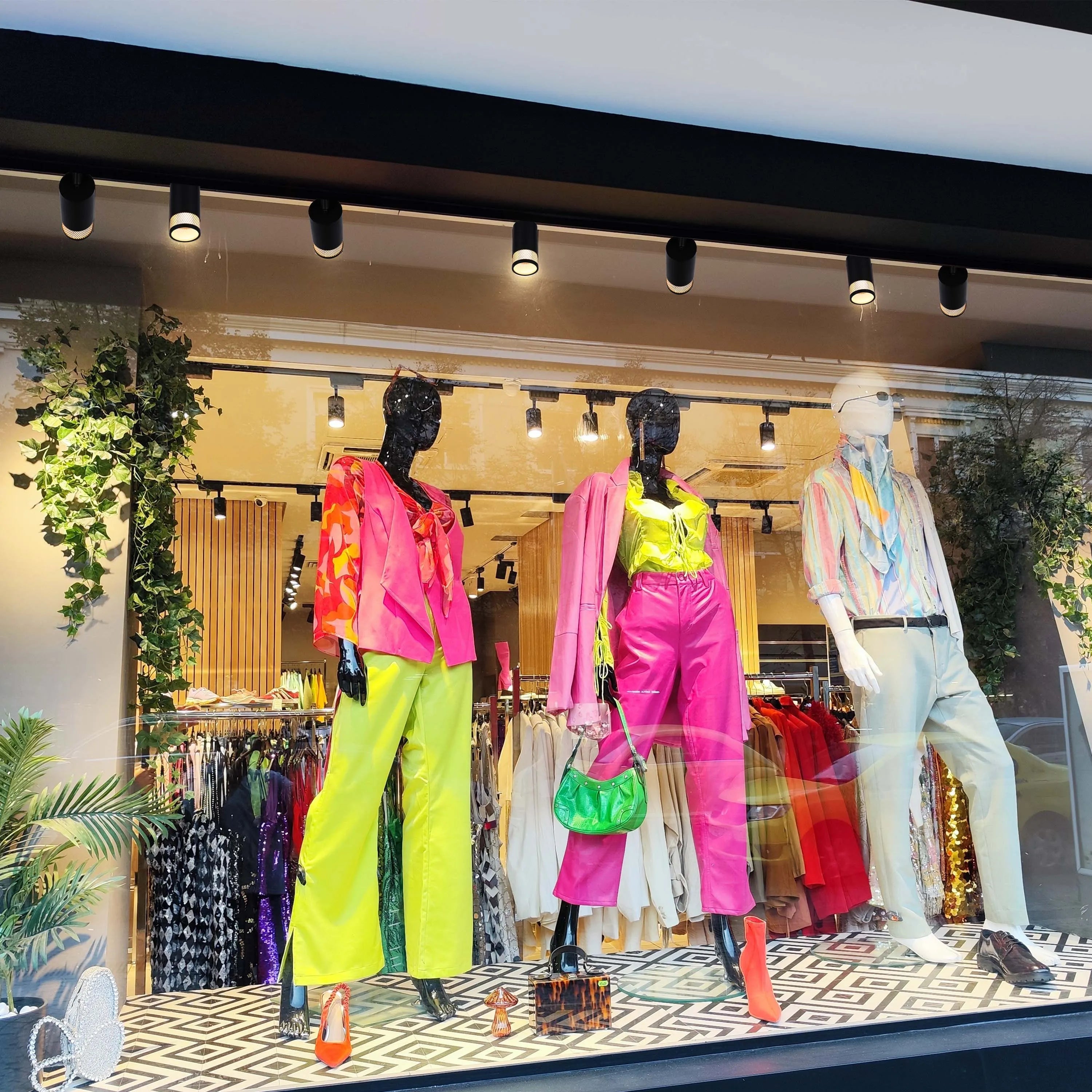 A window display features track lighting illuminating colourful mannequins and clothing, creating a bright and vibrant shopping experience.