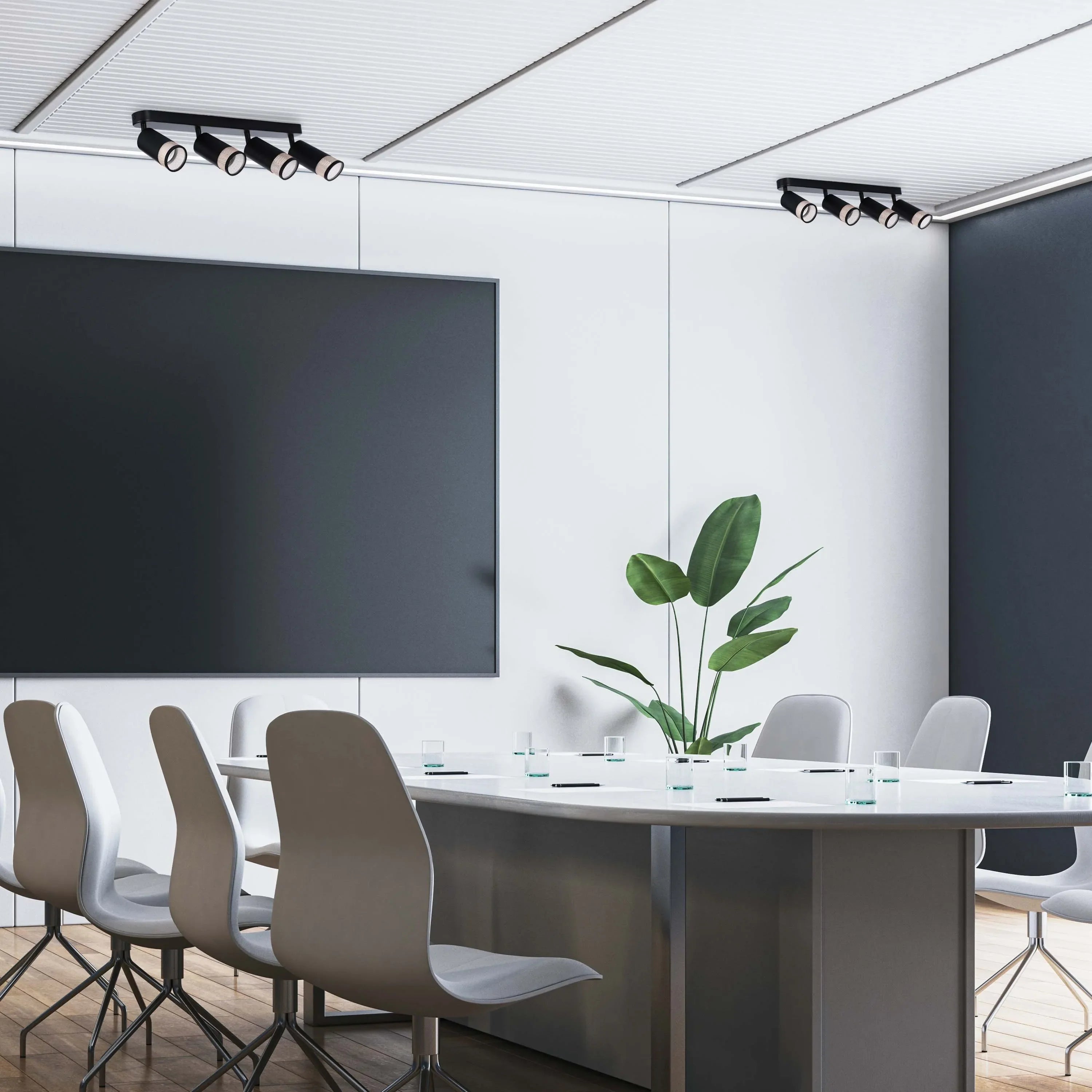 A modern conference room features two track lighting fixtures with four adjustable spotlights each, providing focused illumination.