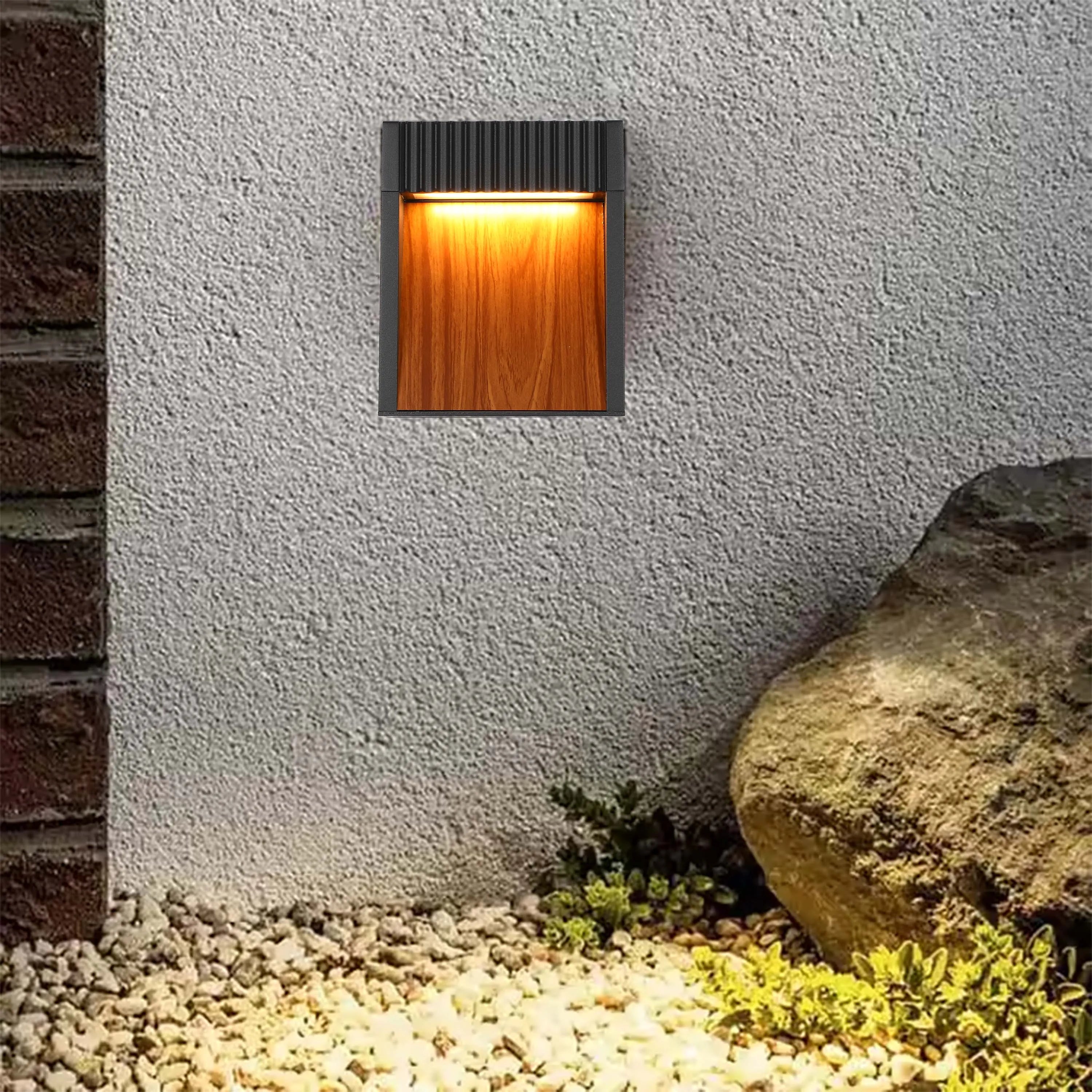 A stylish wall light emits a warm, inviting glow, highlighting the textured wall and adding ambience to the outdoor space.