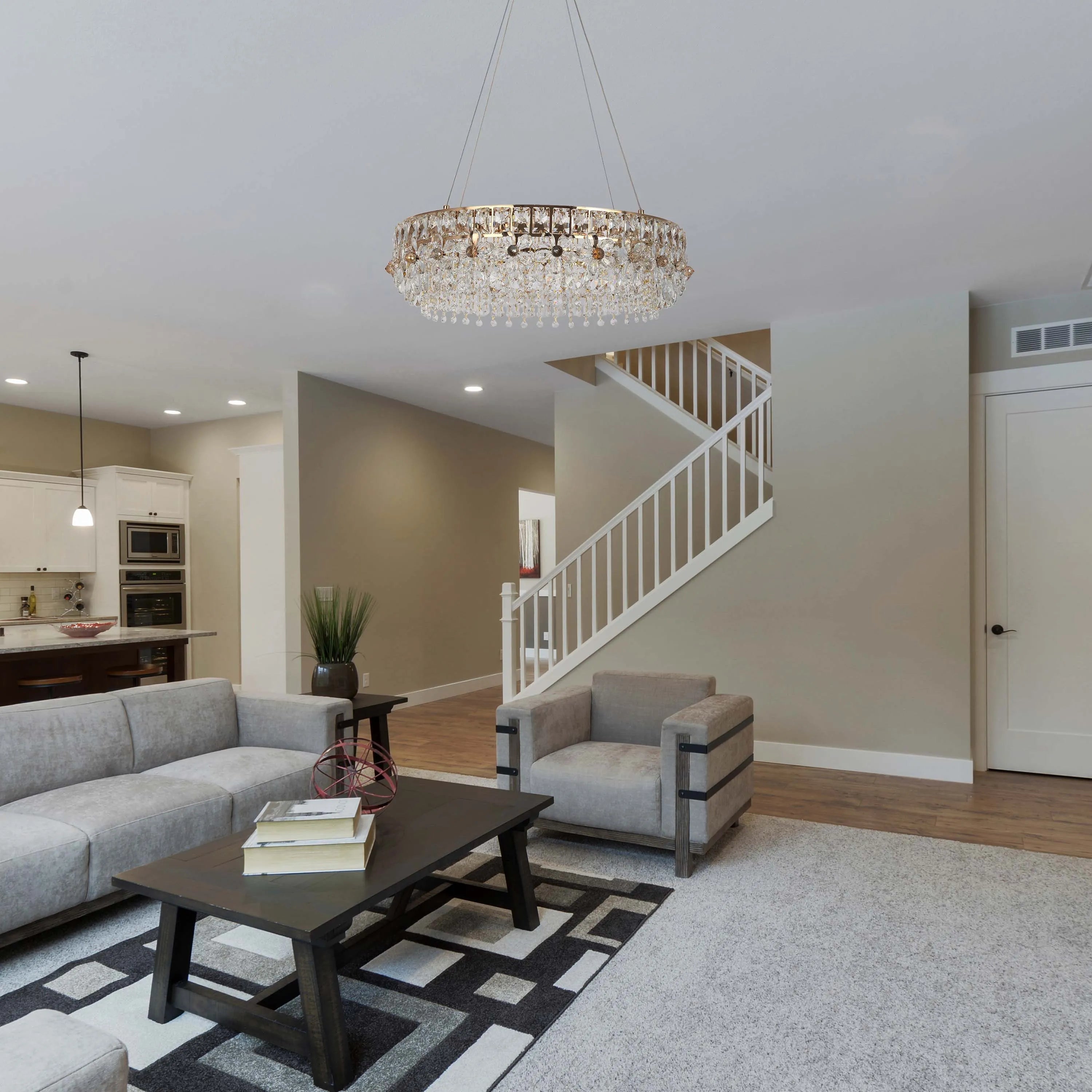 A dazzling crystal chandelier hangs above a stylish living space. Kitchen lighting complements the room's bright ambiance.
