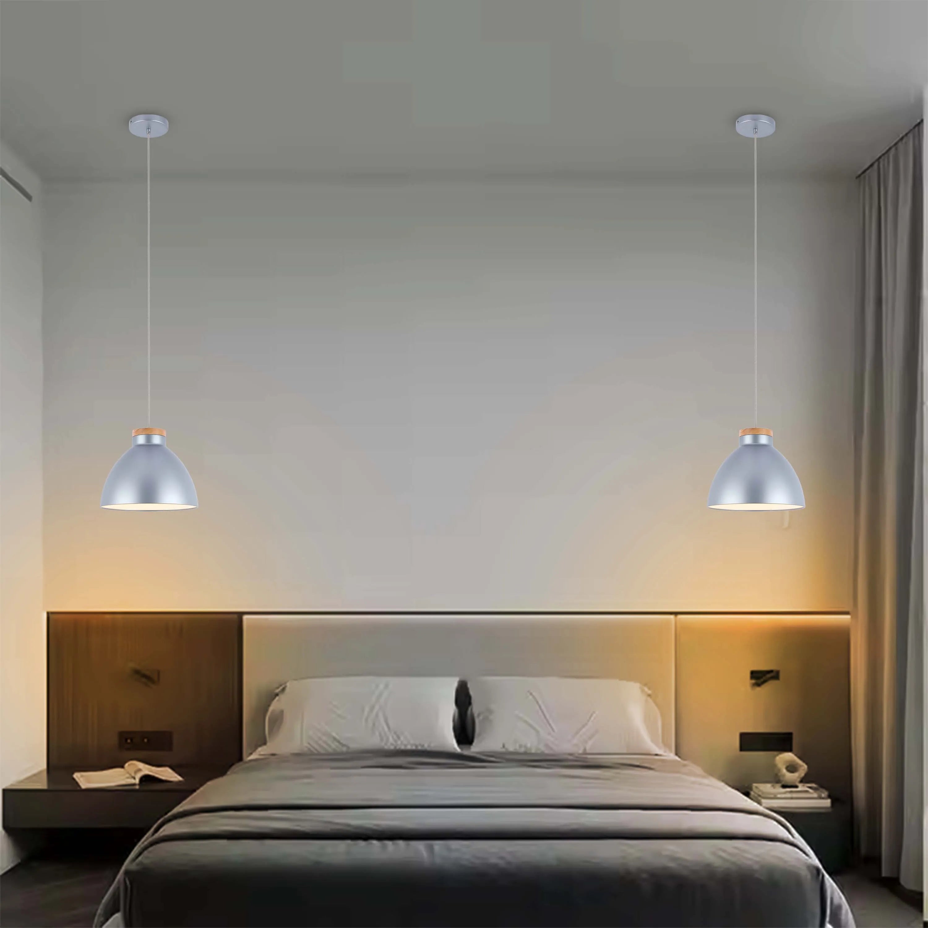 Two silver pendant lights hang above bedside tables either side of a large double bed in a modern bedroom.