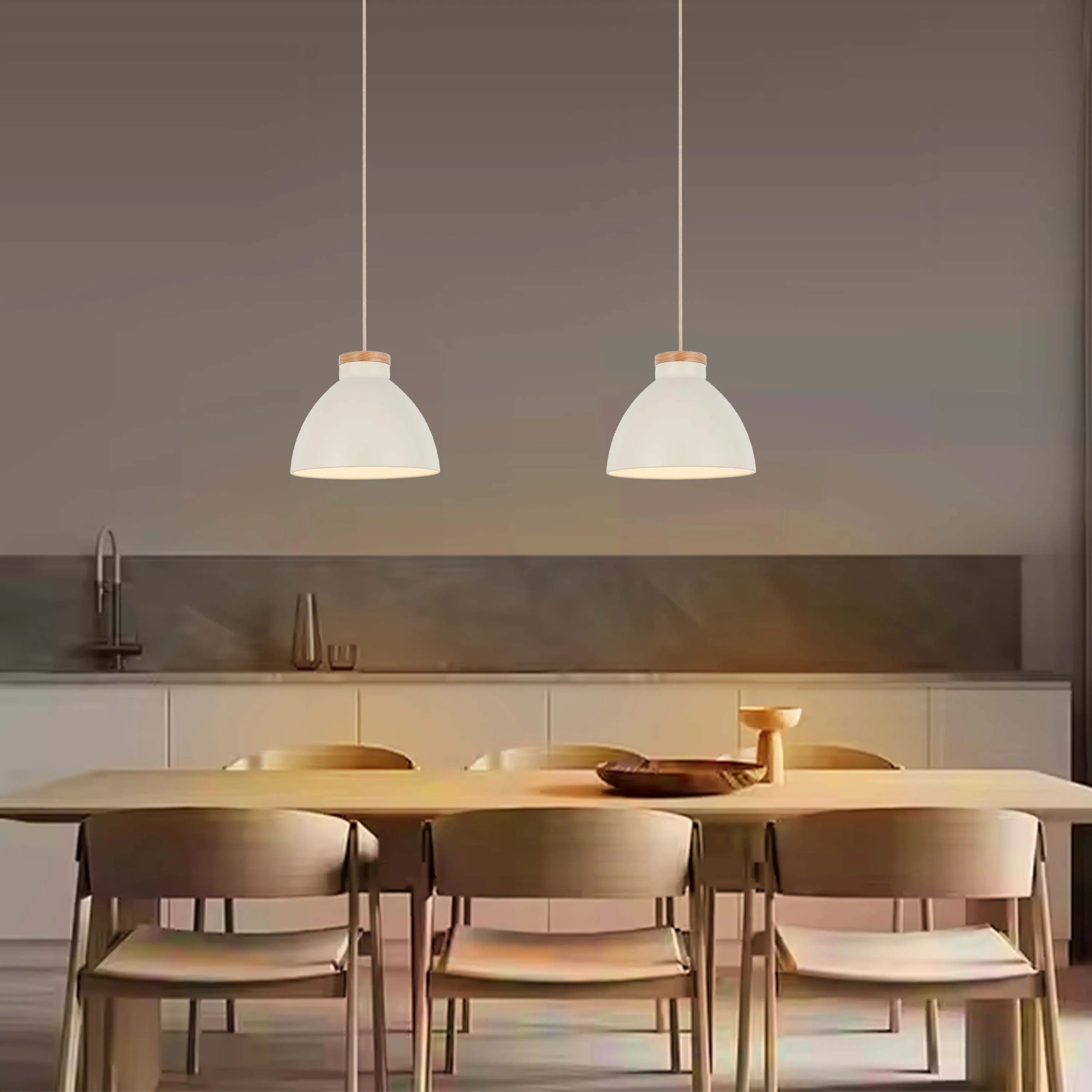 Two white pendant lights hang over a wooden table and chairs, illuminating the scene with a warm glow.