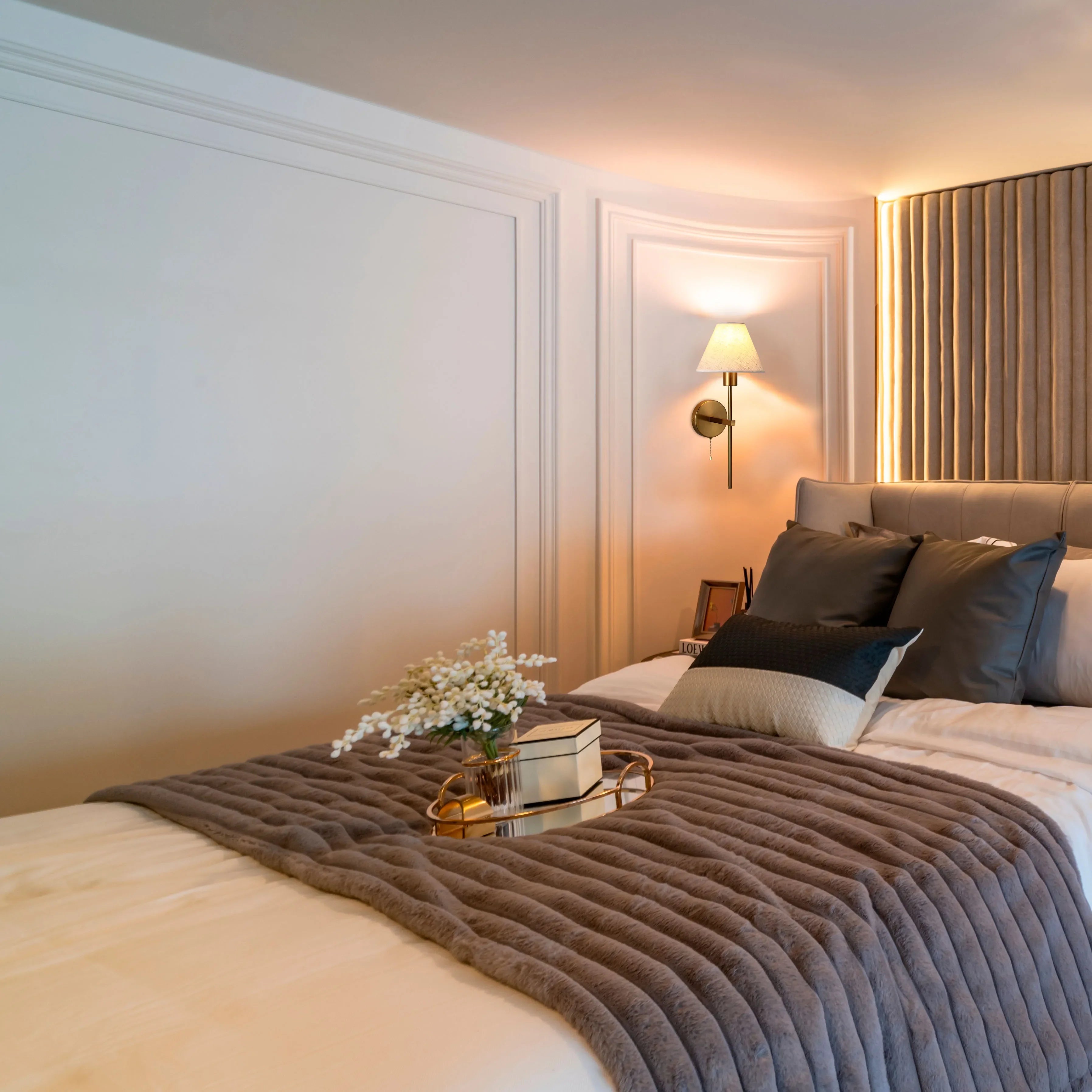 Soft ambient lighting from a wall sconce and headboard feature creates a cosy, inviting bedroom atmosphere.