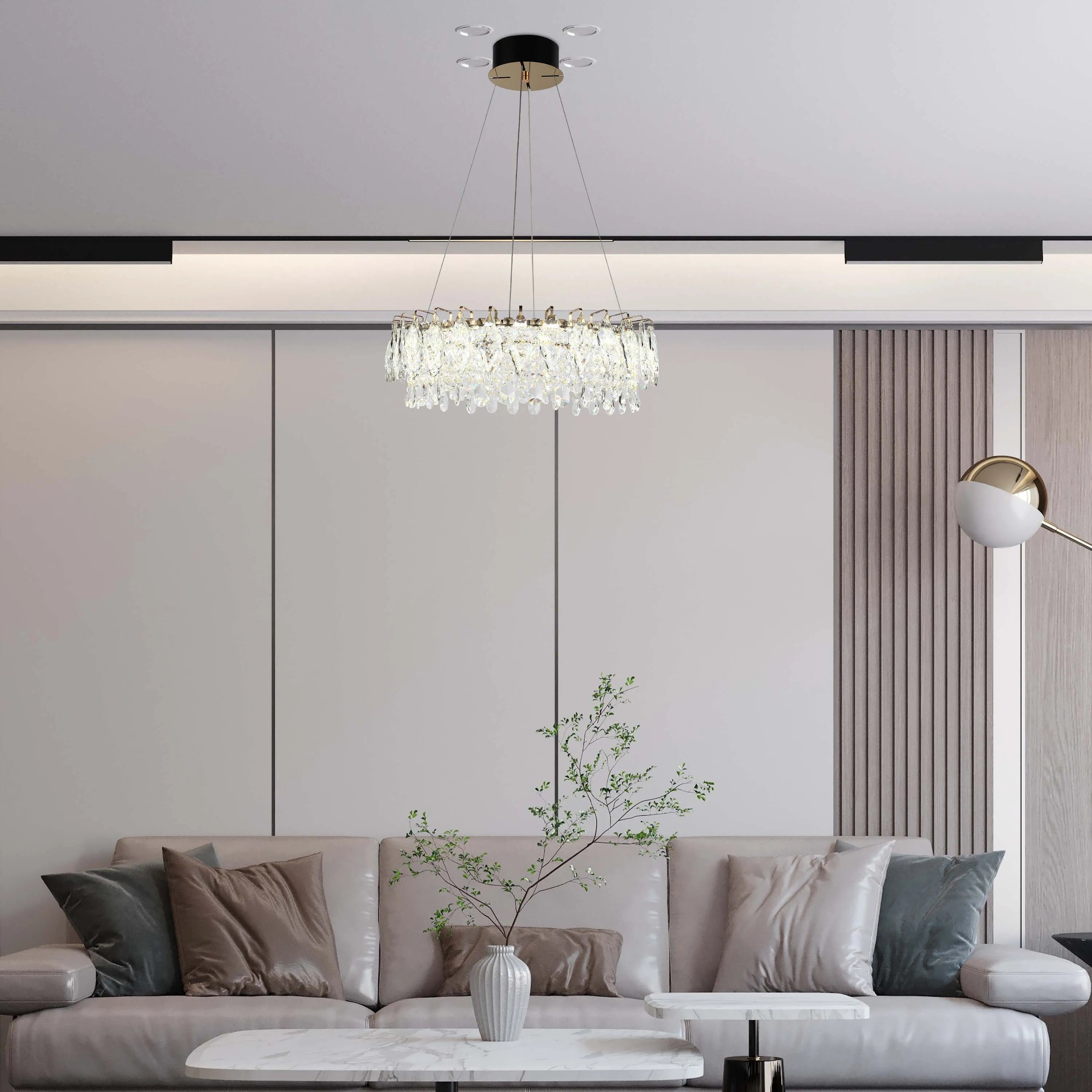A modern crystal chandelier hangs above a living room. Recessed spotlights and a stylish floor lamp provide additional illumination.