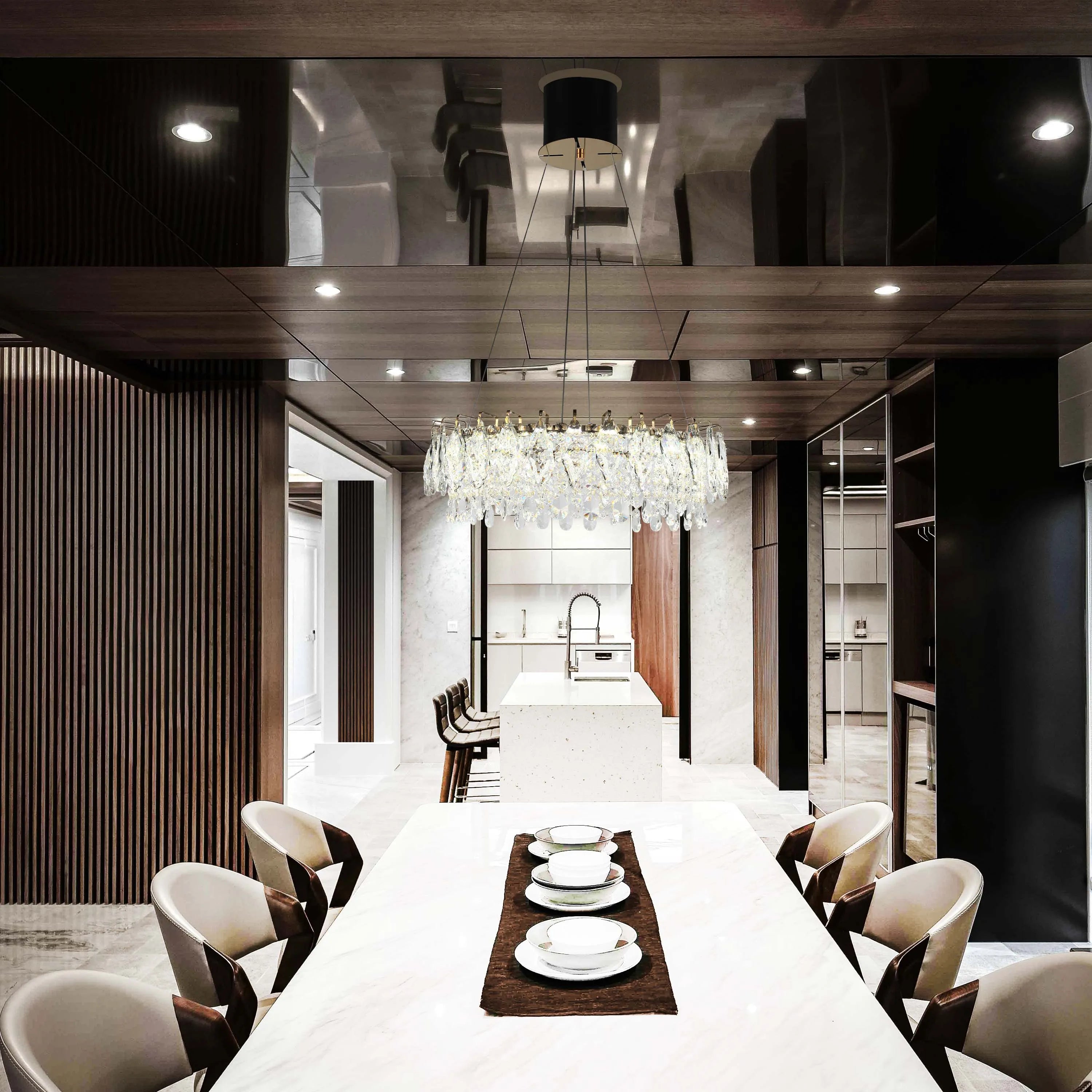 A modern dining room boasts a crystal chandelier above a marble table, complemented by subtle recessed lighting in a glossy ceiling.