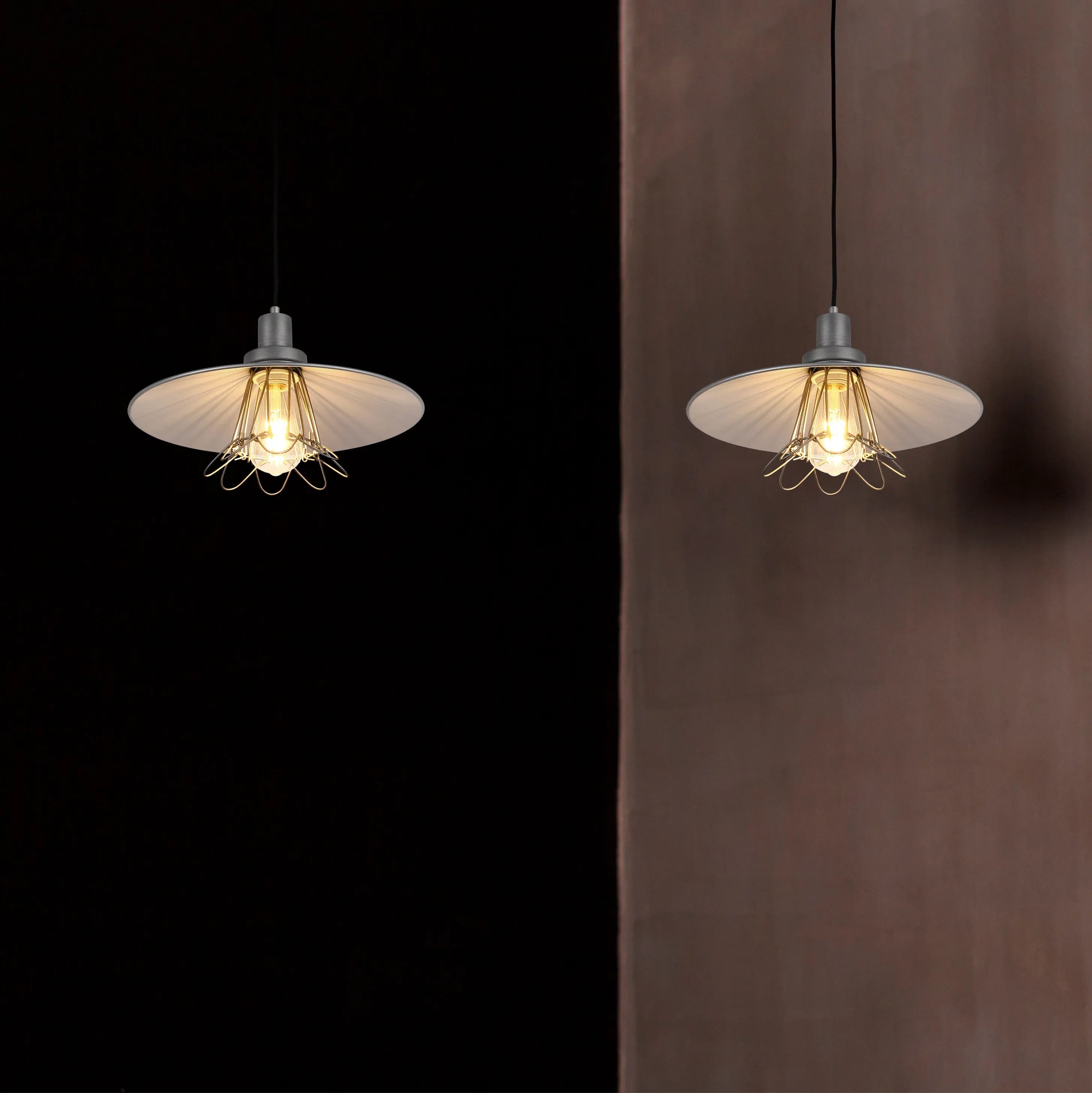 Two industrial pendant lights with metal shades and filament bulbs provide a warm, inviting glow against contrasting dark and neutral backgrounds.