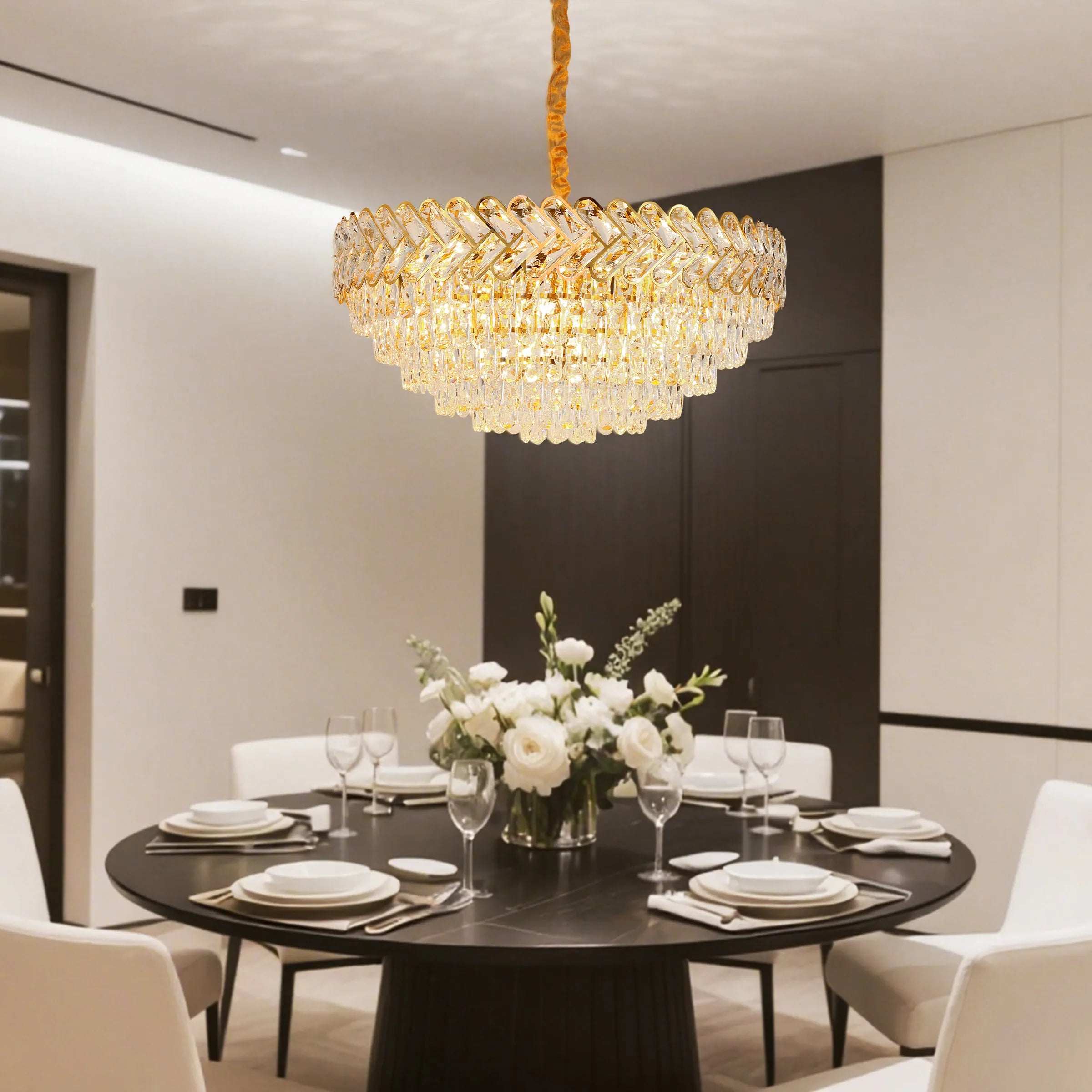Glamorous tiered chandelier with crystal pendants and a gold frame, illuminating a stylish dining room.