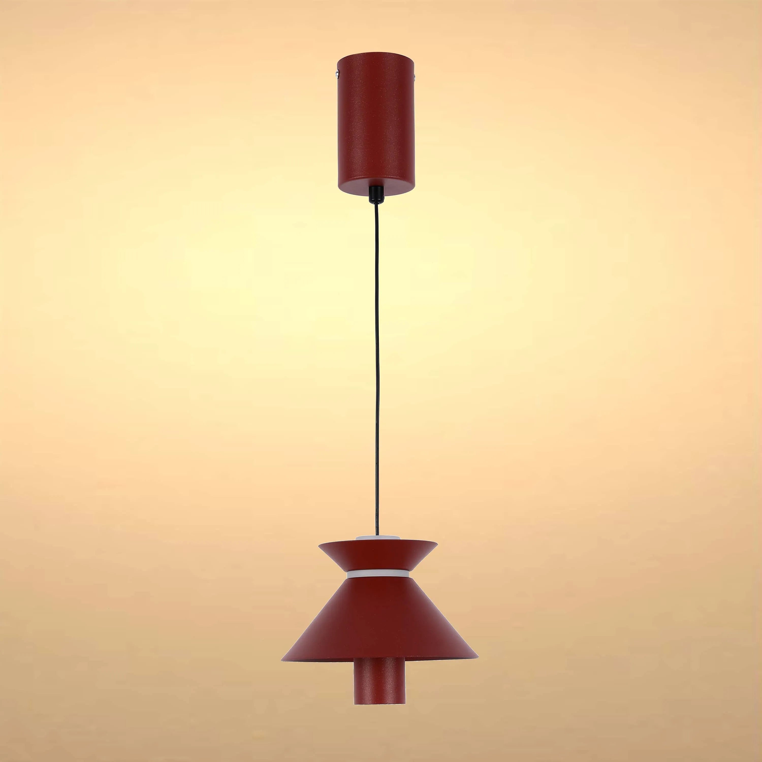 A red, mid-century modern pendant lamp with a cone shade hangs from a slim cable in this studio shot.