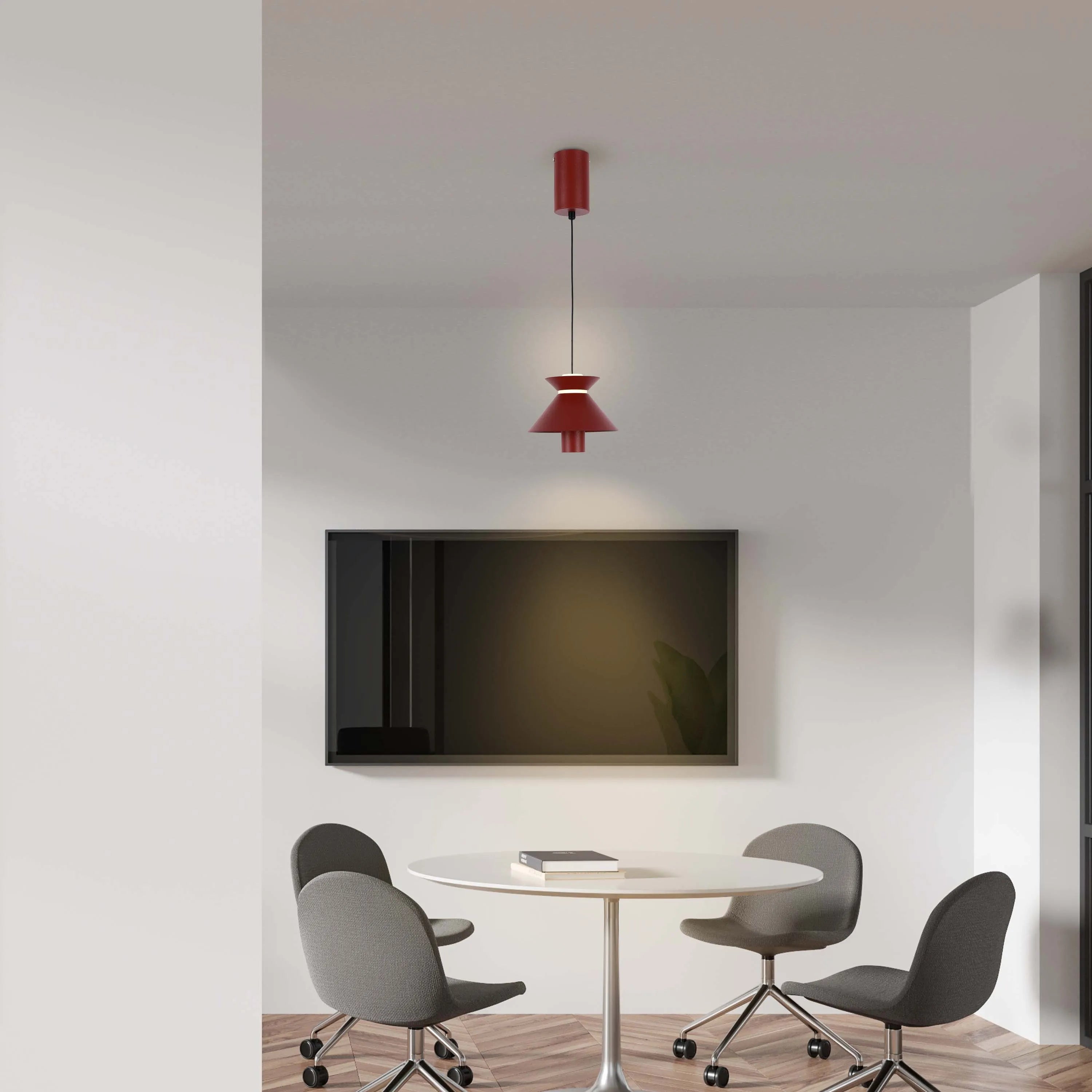 A modern red pendant light hangs above a round white table with grey chairs, providing a stylish and functional lighting solution.