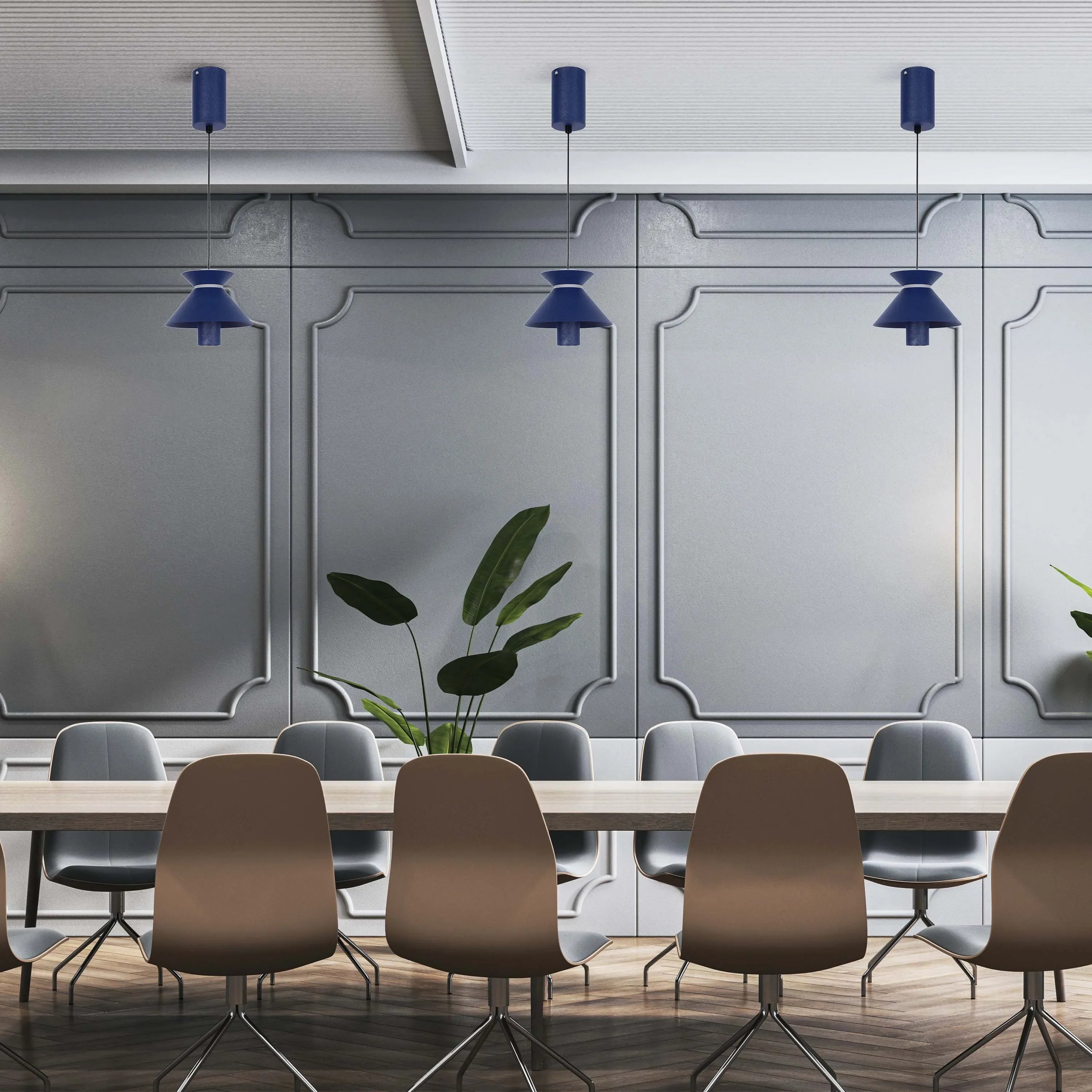 Stylish blue pendant lights hang above a long conference table in a modern office space, illuminating the area with a cool tone.