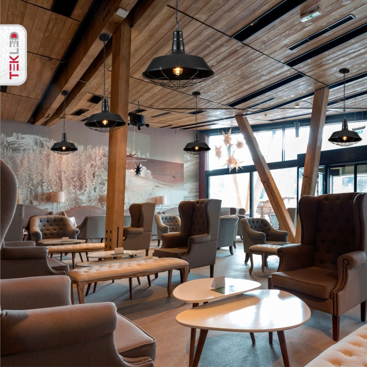 A stylishly arranged lounge area featuring plush armchairs, cushioned benches and sleek coffee tables, all under modern pendant lights.