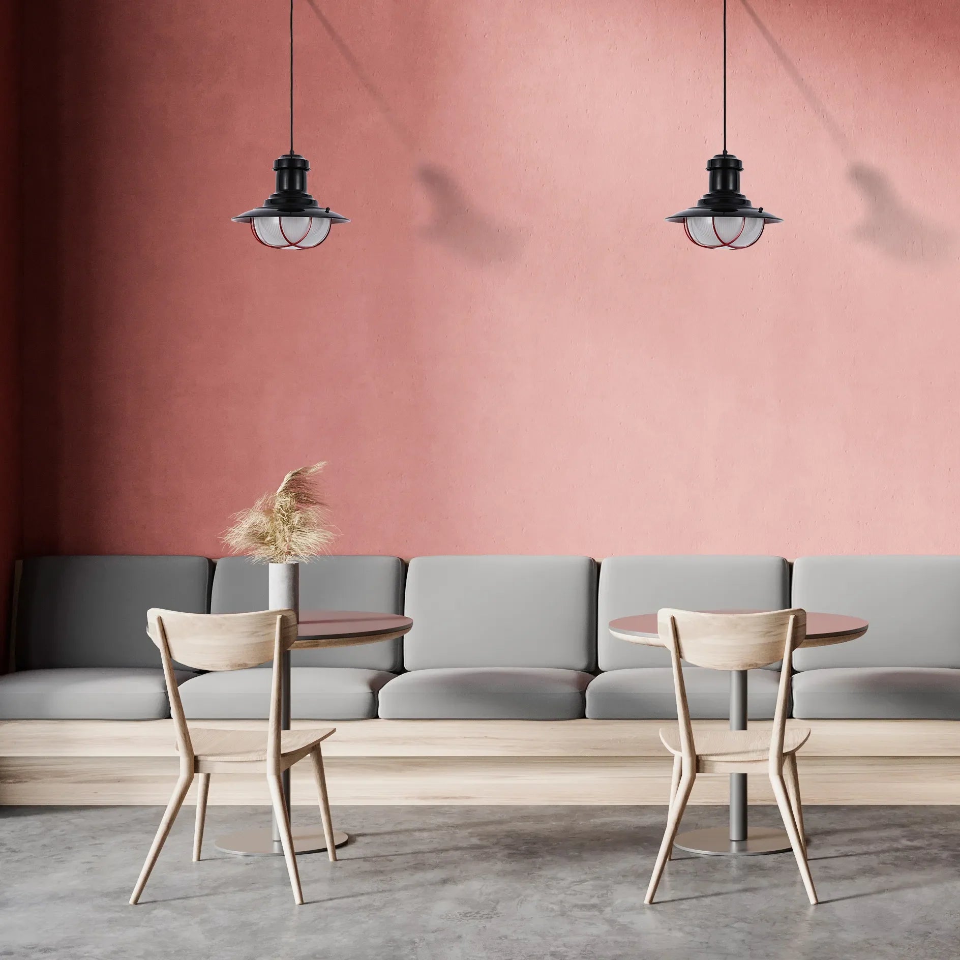 Coastal style pendant lights hang above wooden tables and chairs in a café with a warm pink wall.