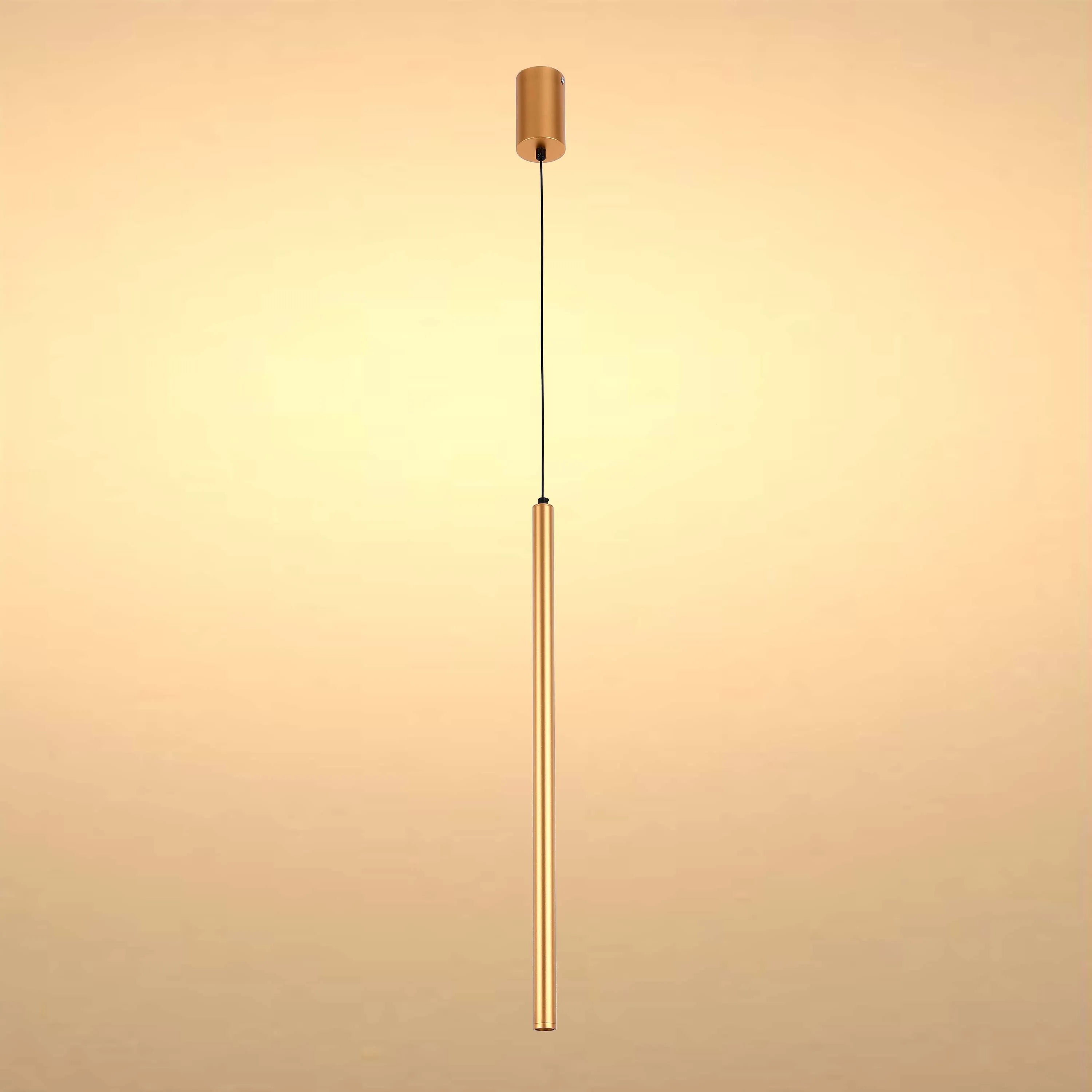 A modern, minimalist gold pendant light fixture with a long, slender cylindrical shade suspended from a black cable.