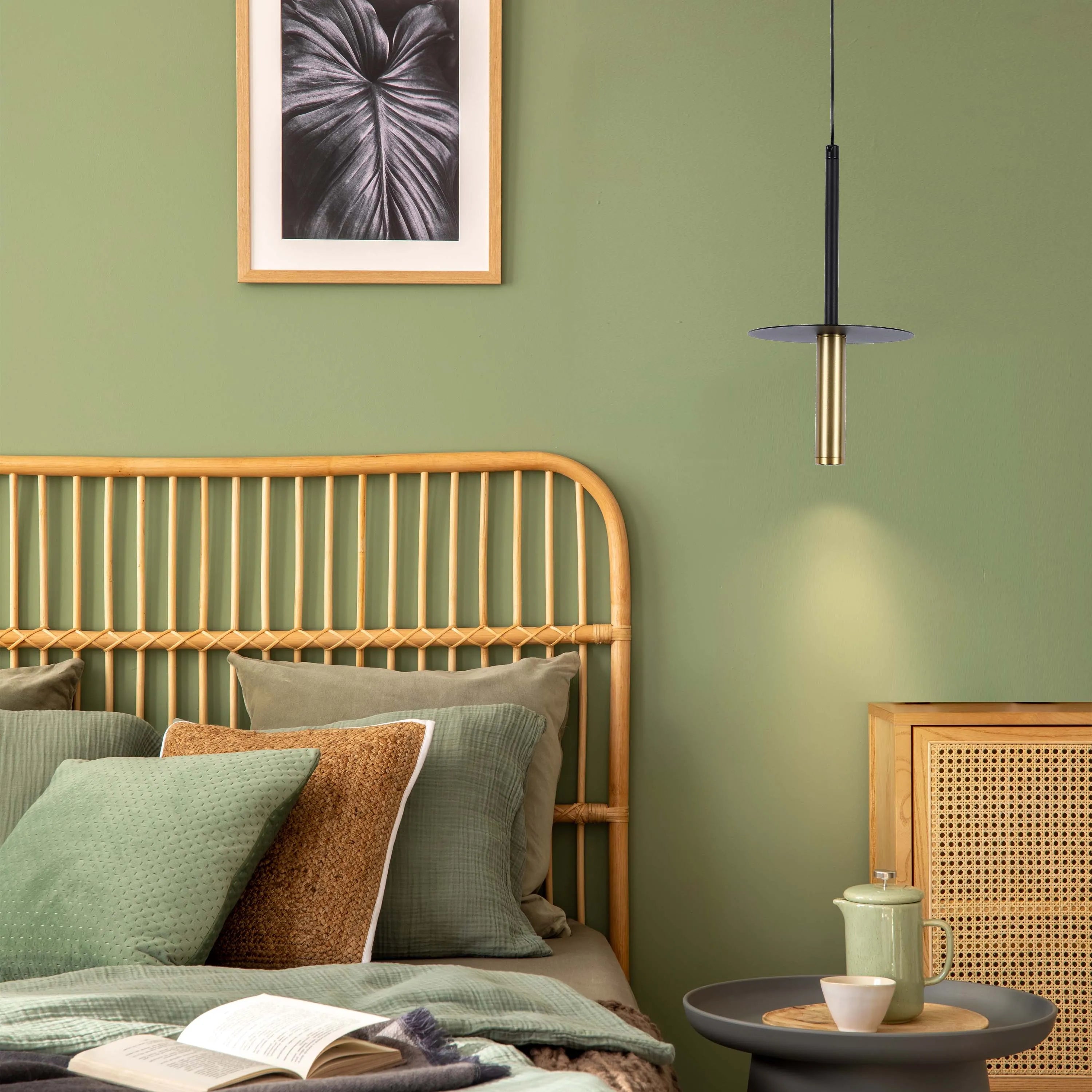 A sleek pendant light fixture with a black and gold finish, casting a warm glow in a stylish bedroom setting.