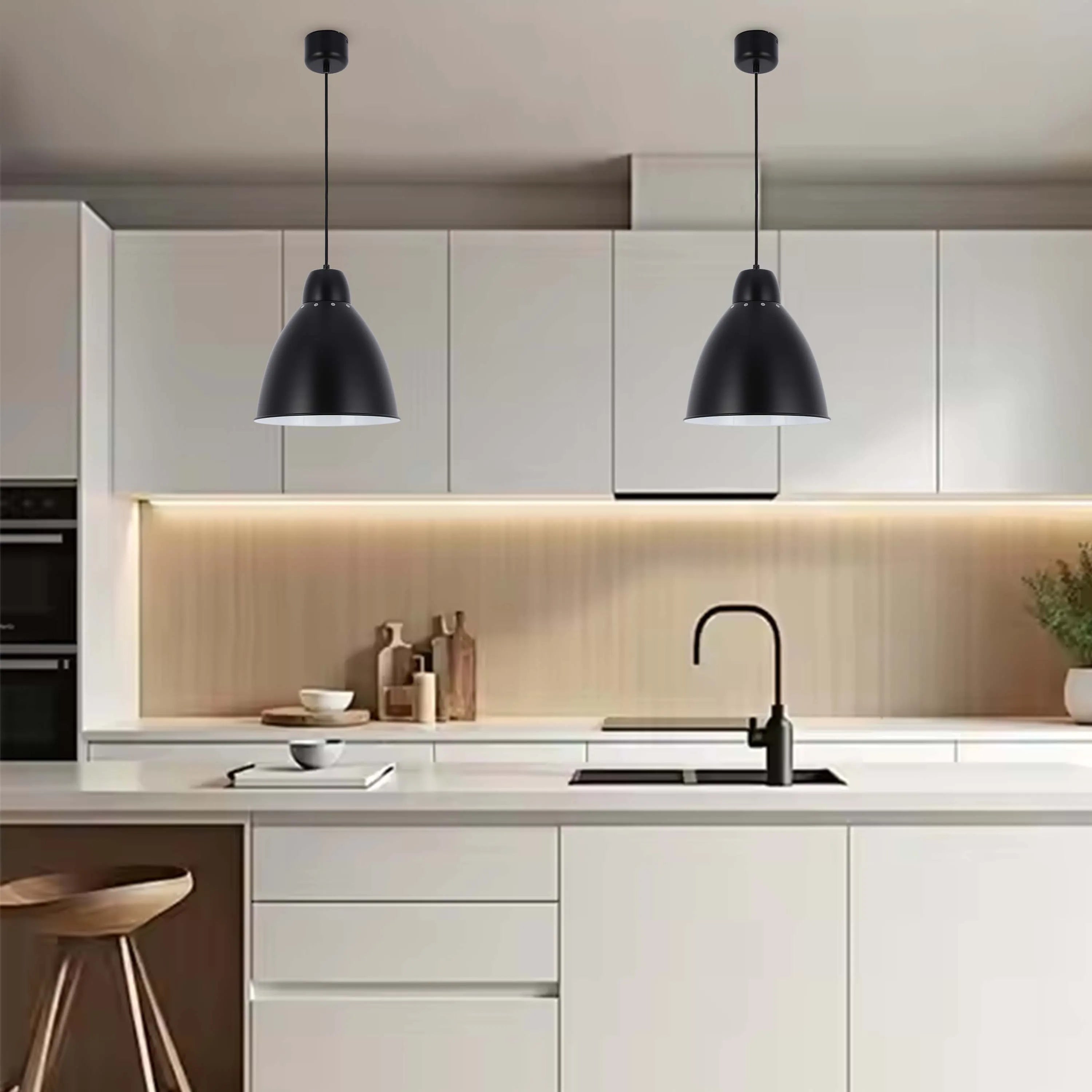 Two modern black pendant lights hang above a bright, minimalist kitchen worktop, providing a stylish and functional lighting solution.