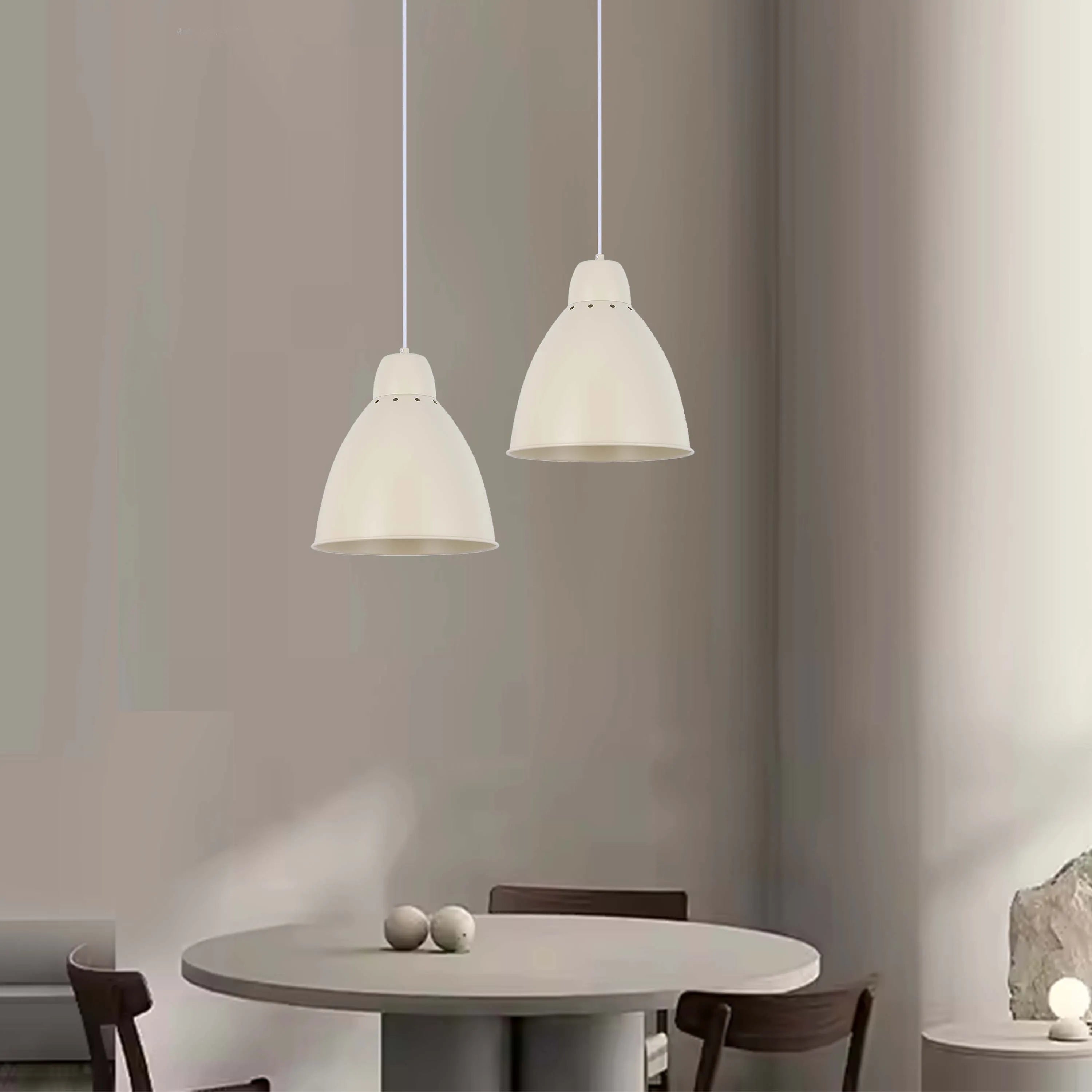 Two dome pendant lights hang above a round table, creating a modern, minimalist aesthetic in a neutral colour palette.
