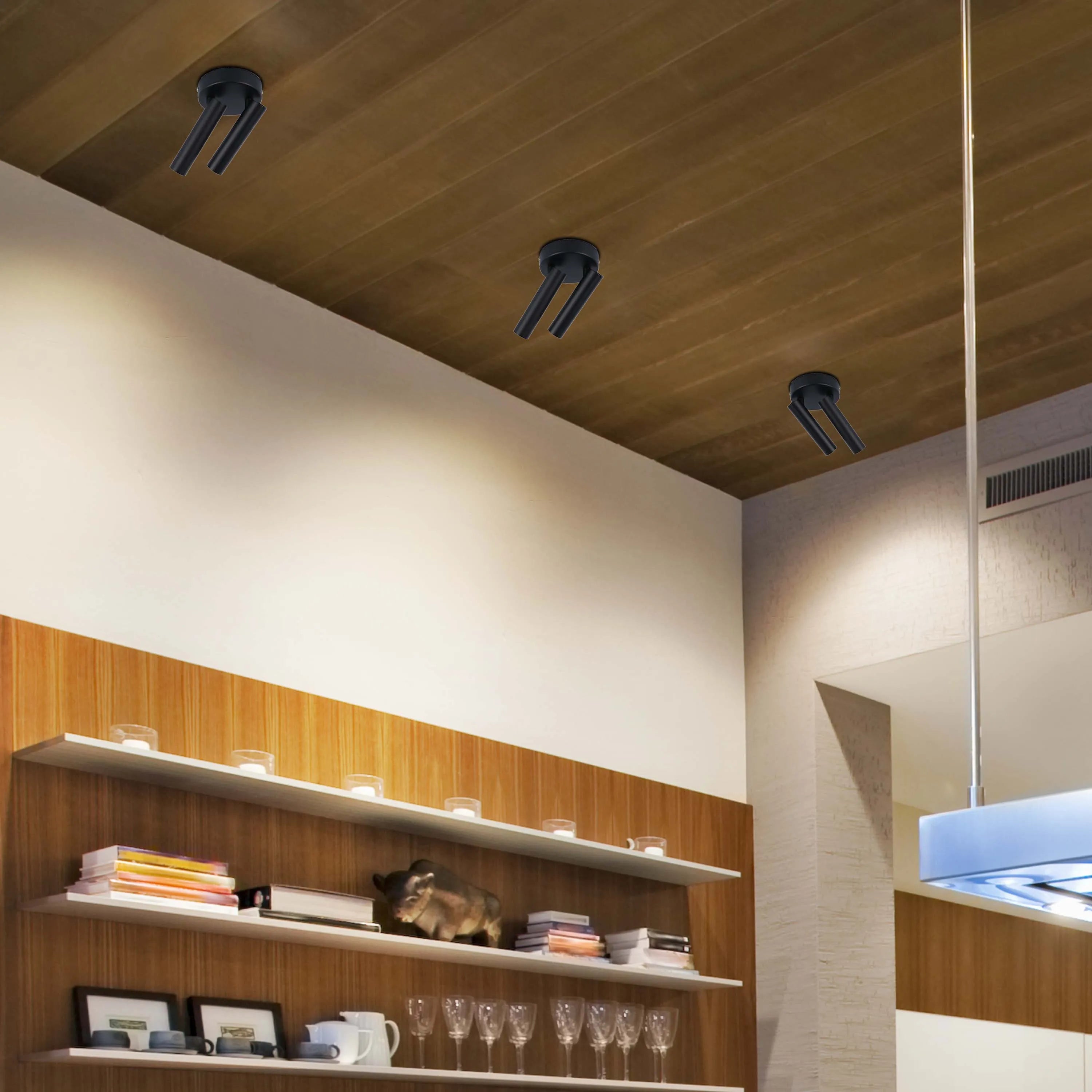 Three black, modern spotlights fixed to a wooden ceiling illuminate a stylish interior, showcasing a blend of form and function.