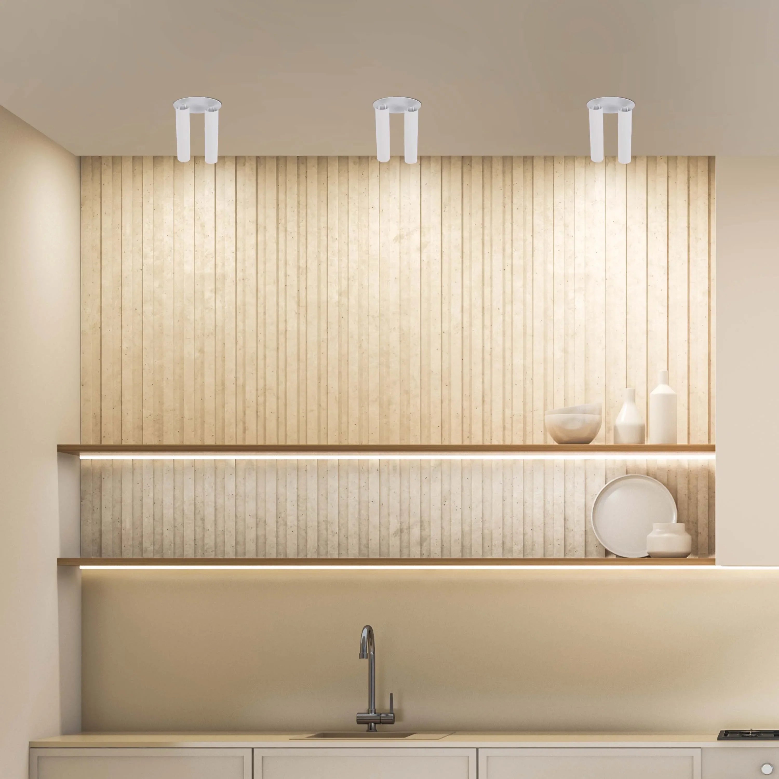 Three modern, white, dual-bulb ceiling lights illuminate a stylish kitchen with sleek counters and shelving.