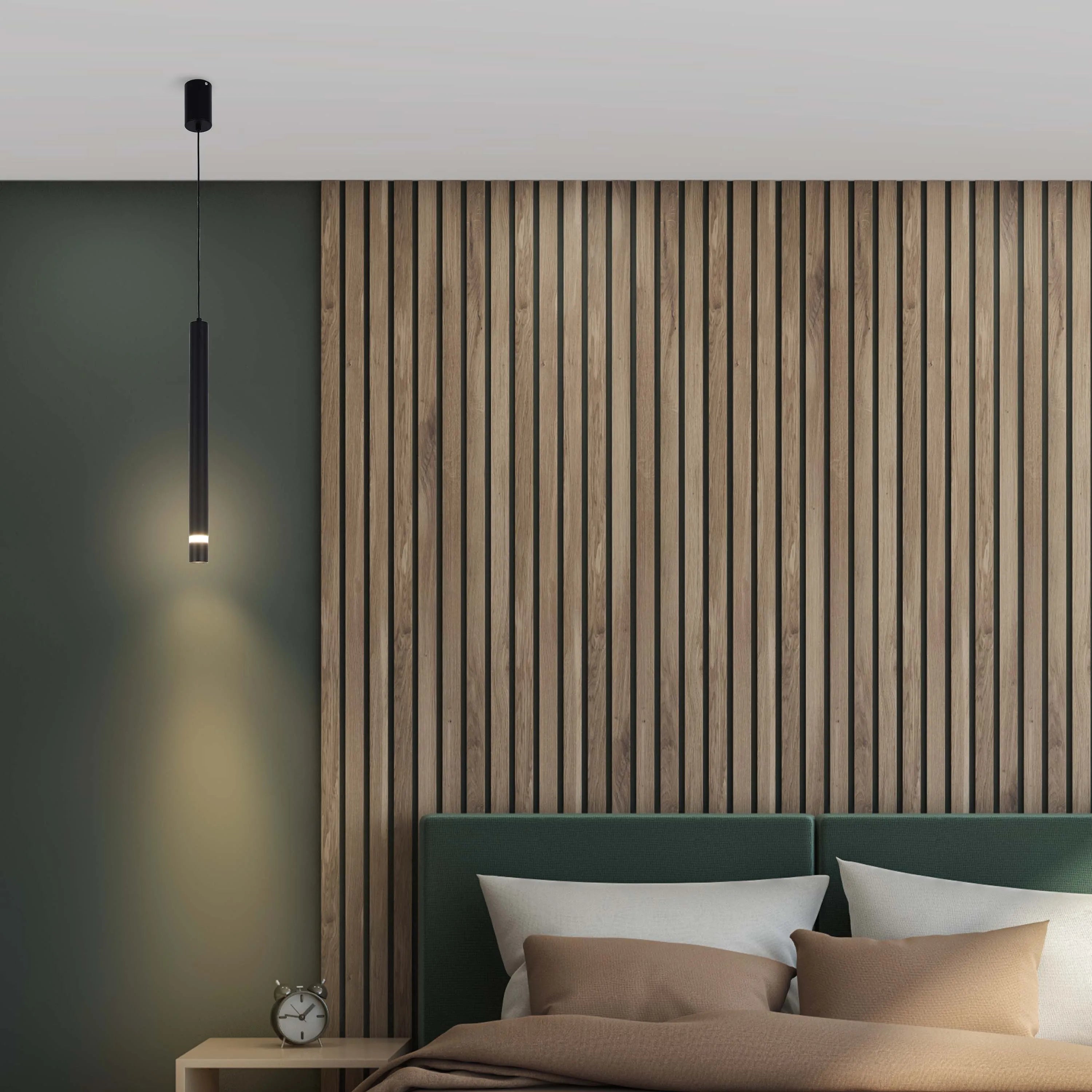 A sleek, black, cylindrical pendant light illuminates the bedside table, casting a warm glow on the green wall and wooden panelling.