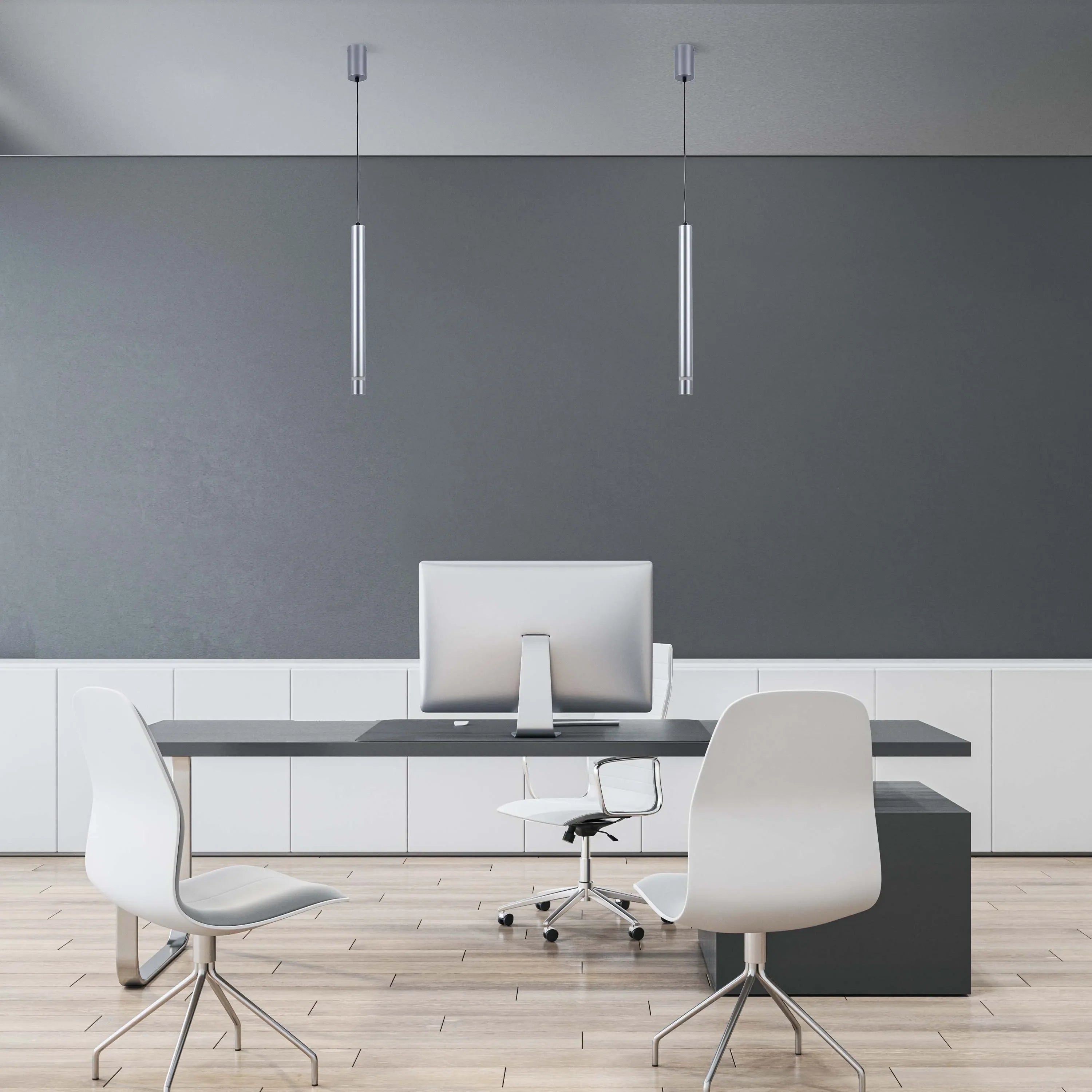 Modern office lighting: Two silver, cylindrical pendant lights hang above a desk with a computer and chairs, offering focused illumination.
