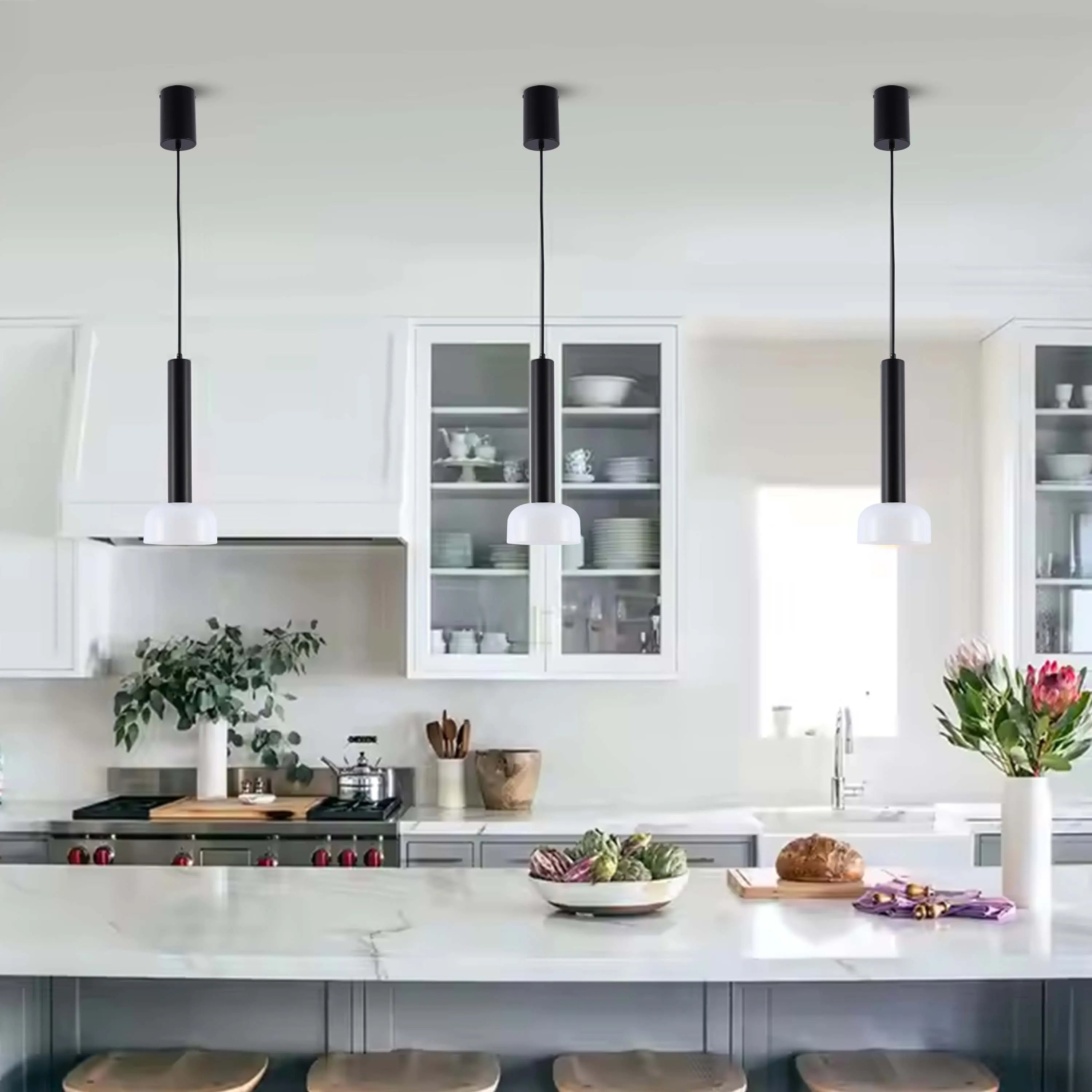 Three stylish pendant lights with a black stem and white globe hang above a kitchen island, providing focused illumination.