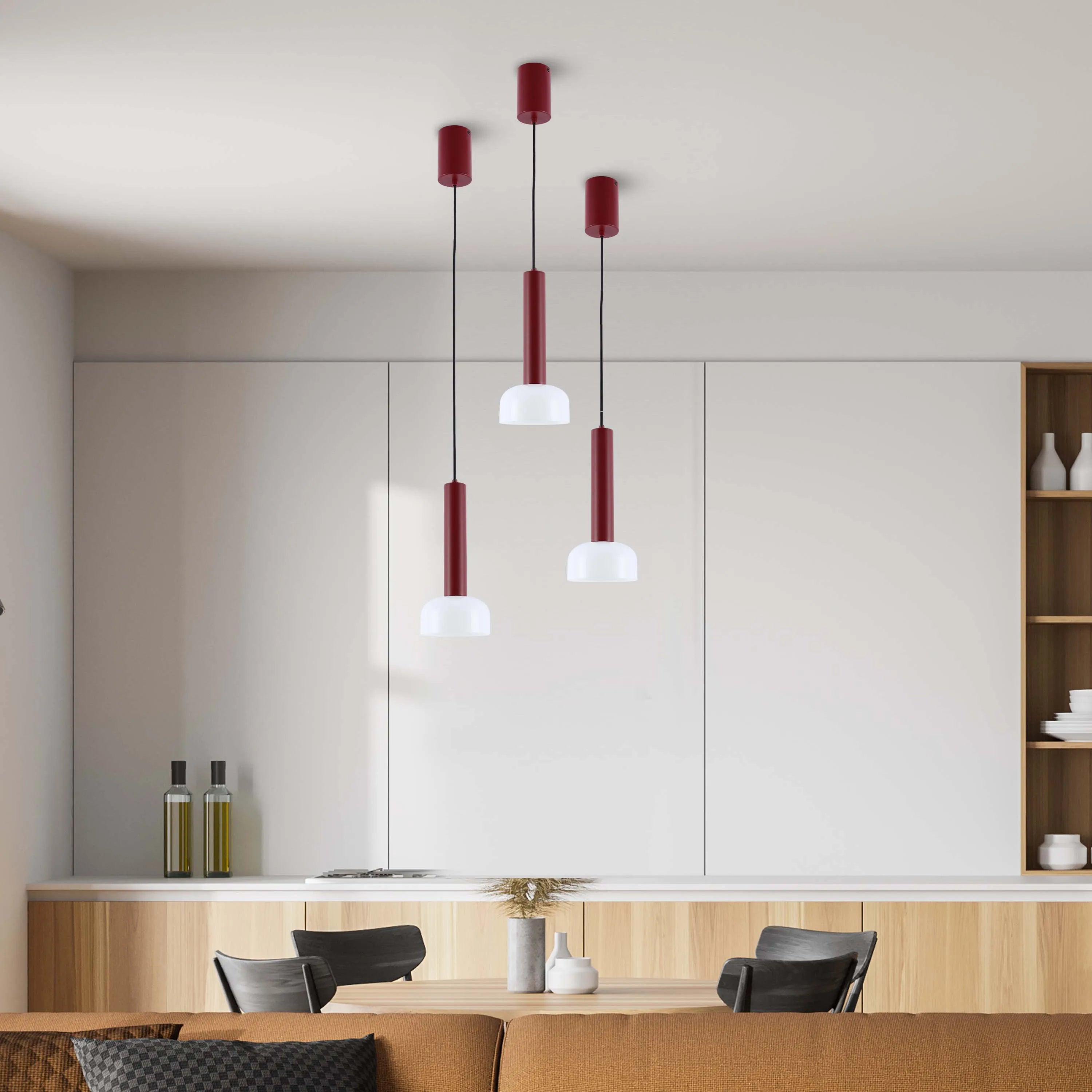 Three stylish red and white pendant lights hang above a modern dining table. Contemporary design lighting.