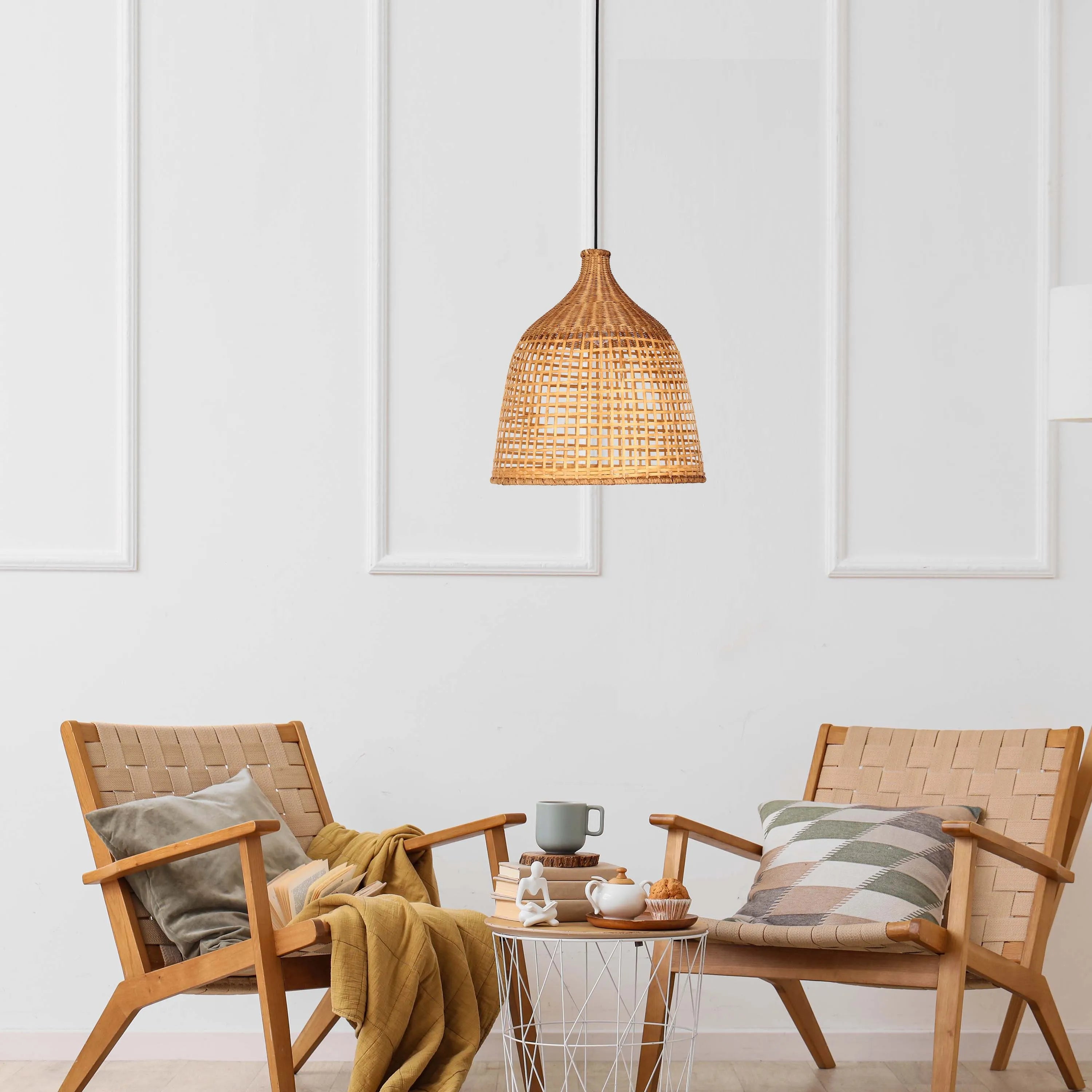 A woven wicker pendant light hanging over a seating area with two chairs and a wire side table, creating a cosy ambiance.