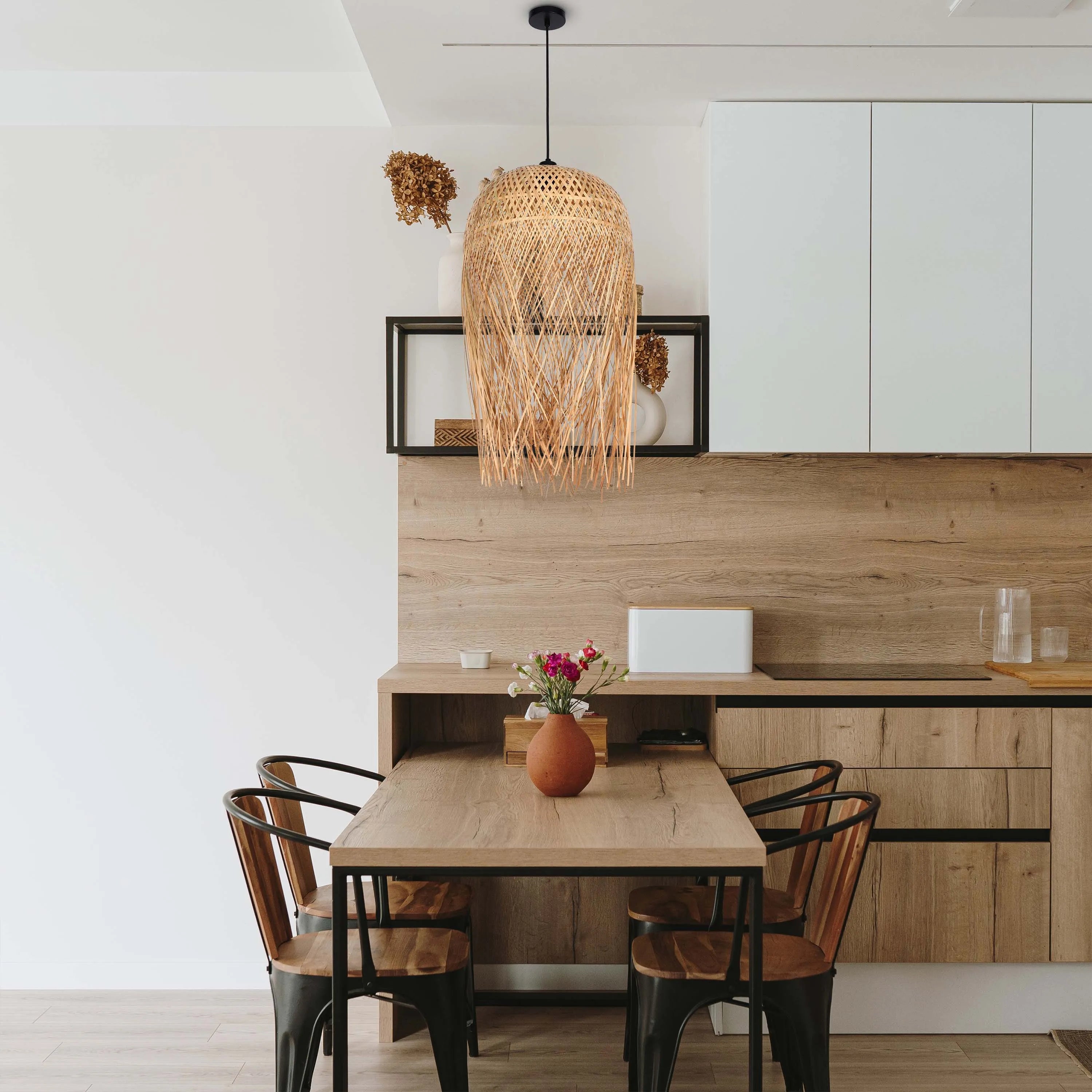 A rattan pendant light hangs above a wooden table and chairs, creating a warm and inviting atmosphere.