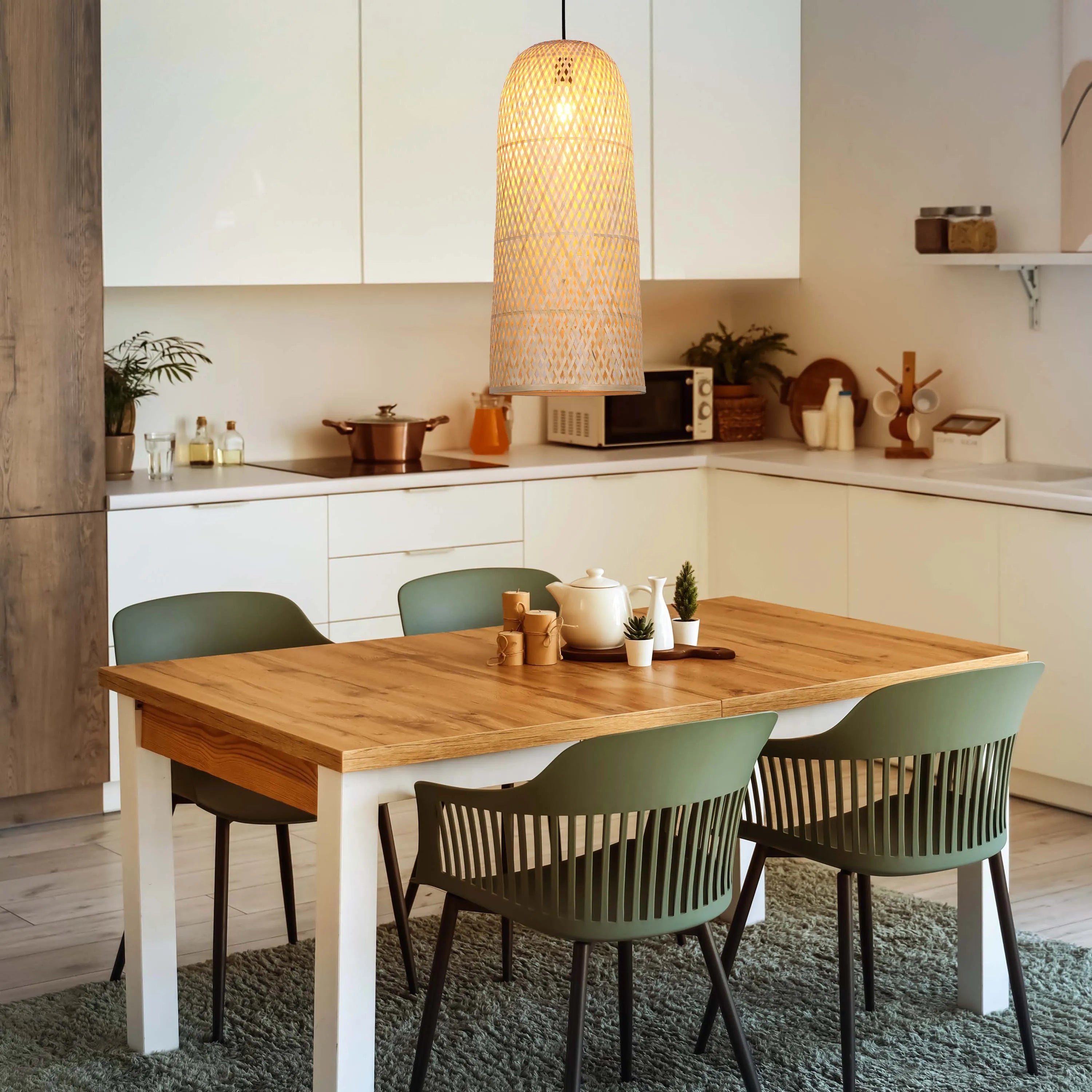 A warm, woven pendant light hangs above a dining table, casting a gentle glow in this modern kitchen.