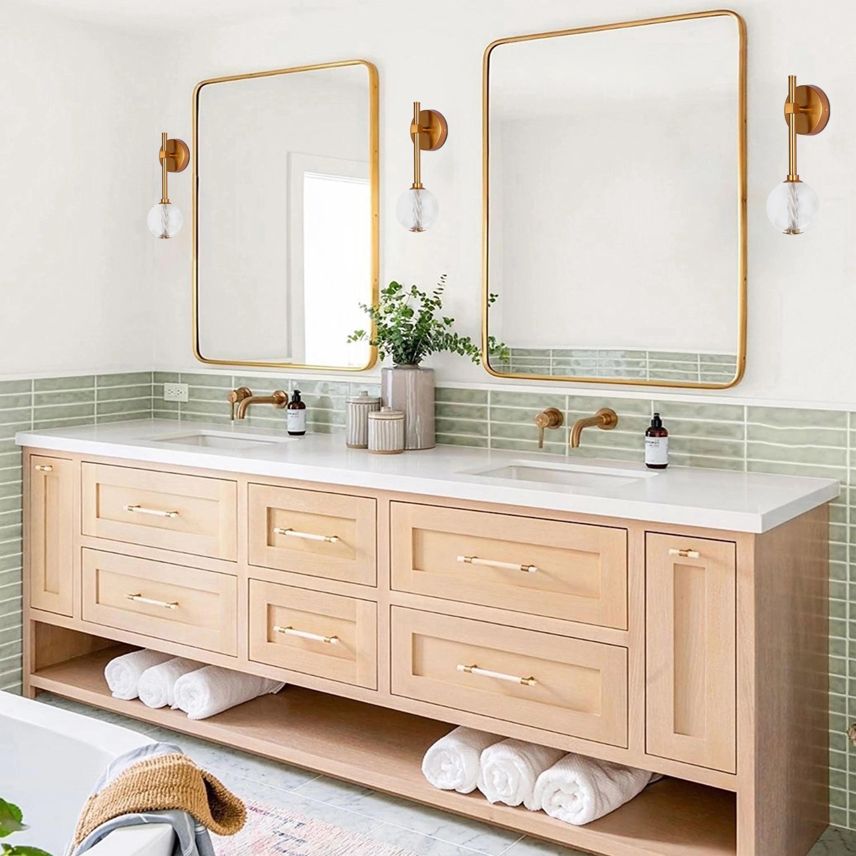 Bathroom vanity with two gold framed mirrors, each with a gold wall light with clear glass shades. Light and airy feel.