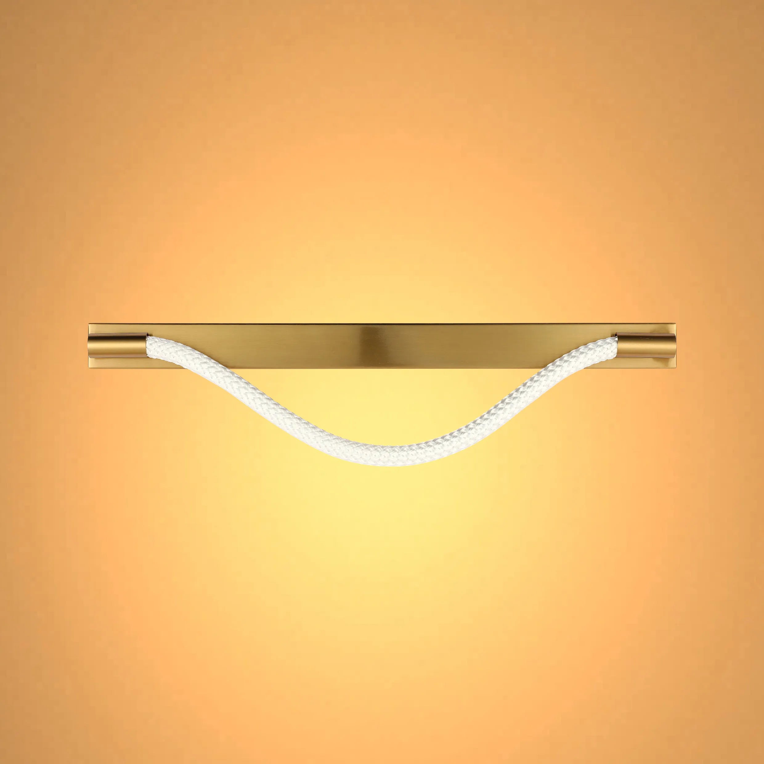 A modern light fitting with a gold fixture and a white rope element, casting a warm and inviting glow.