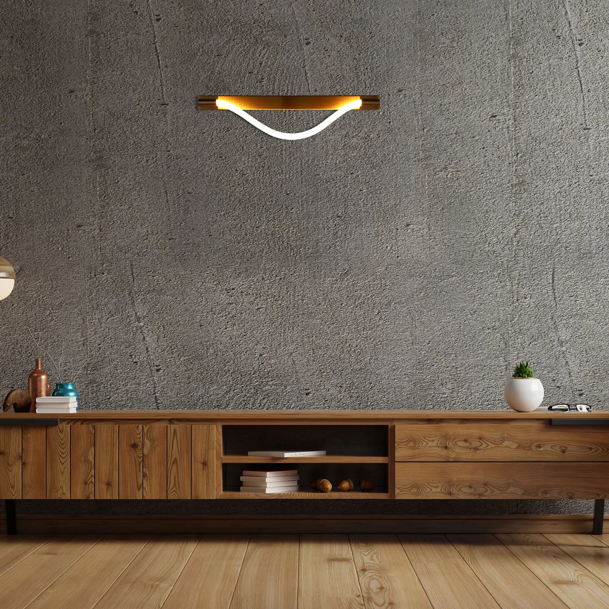 A curved, modern wall light in gold and white, set against a textured grey wall in a contemporary room.