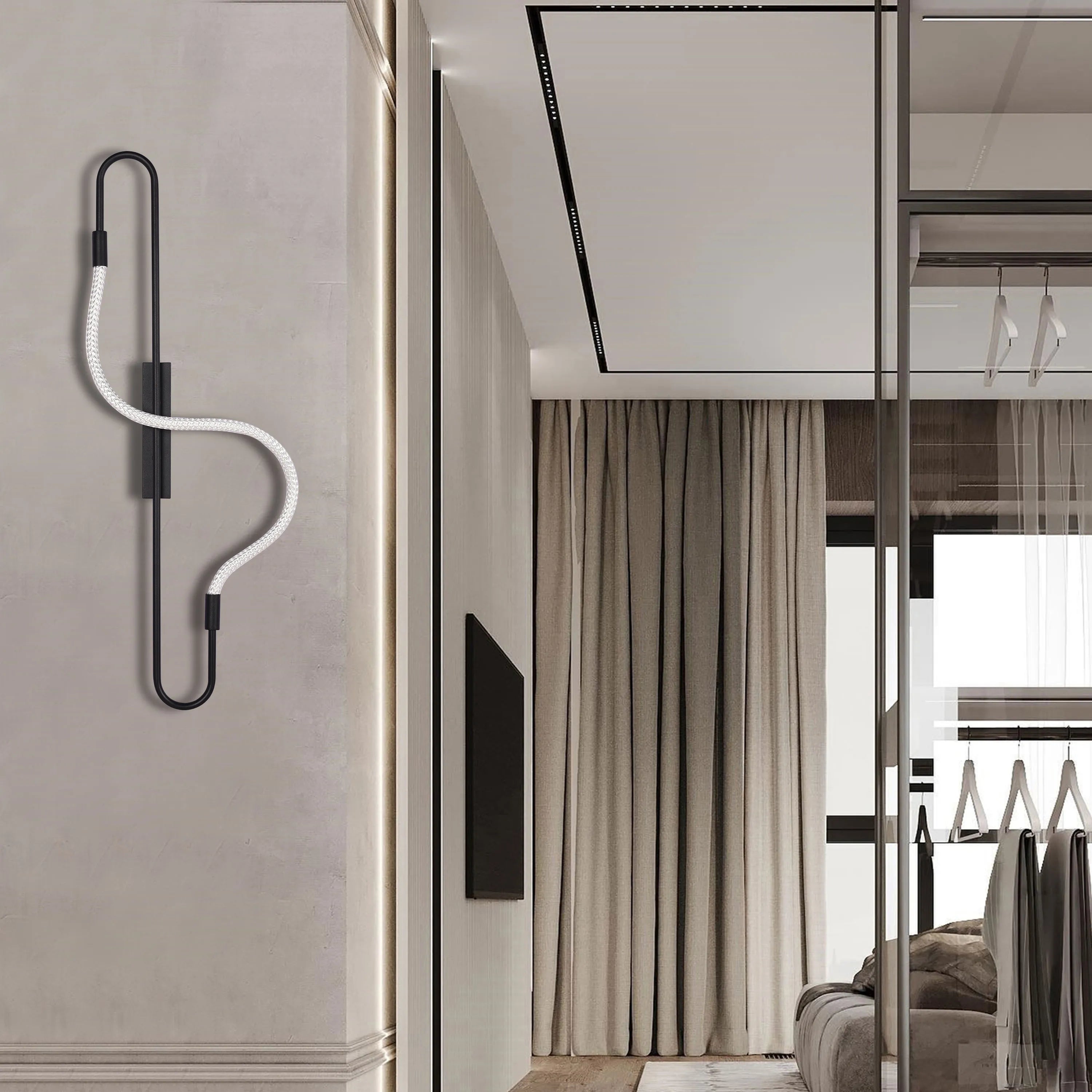 A black modern wall lamp with a twisted white flex wire provides accent lighting in this stylish bedroom.