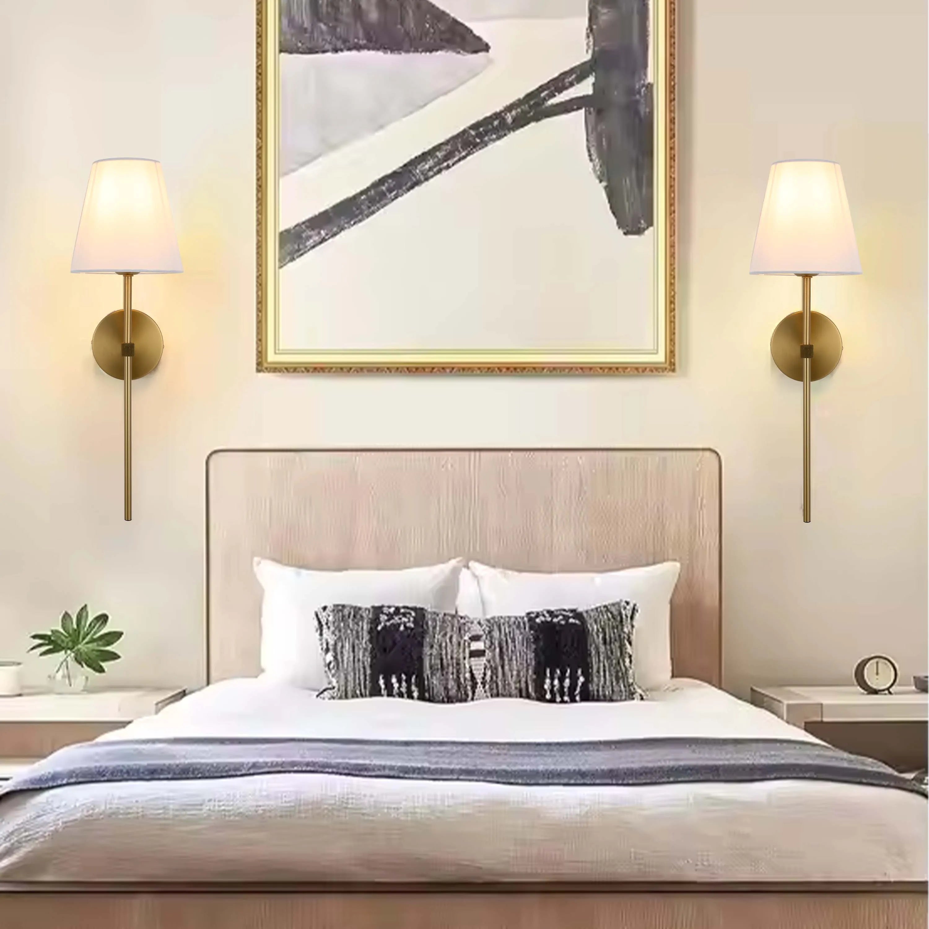 A pair of elegant brass wall lamps provide soft, warm illumination in this sophisticated bedroom setting.