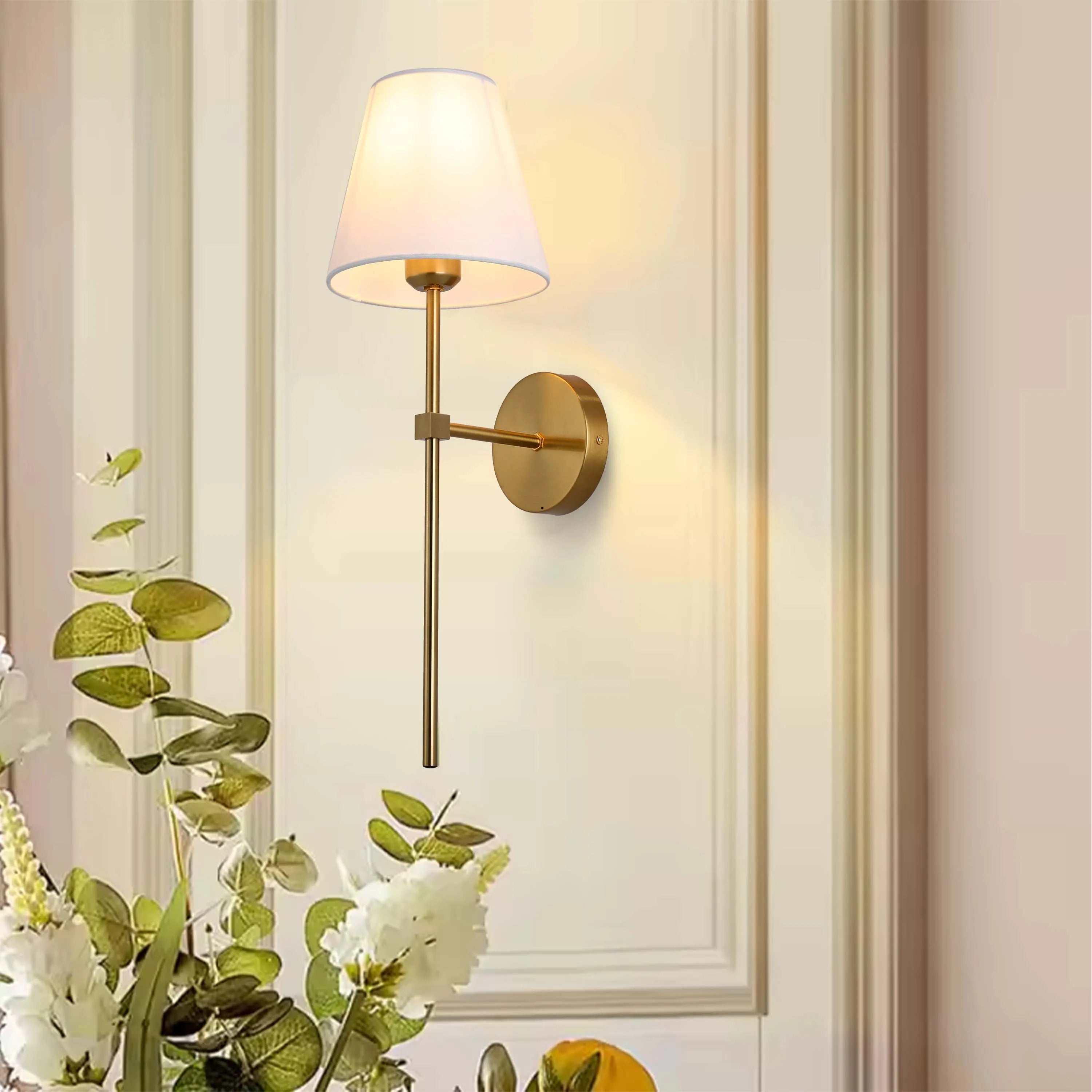 Wall-mounted lamp with a white shade and warm illumination. Modern design suitable for bedrooms and living spaces.
