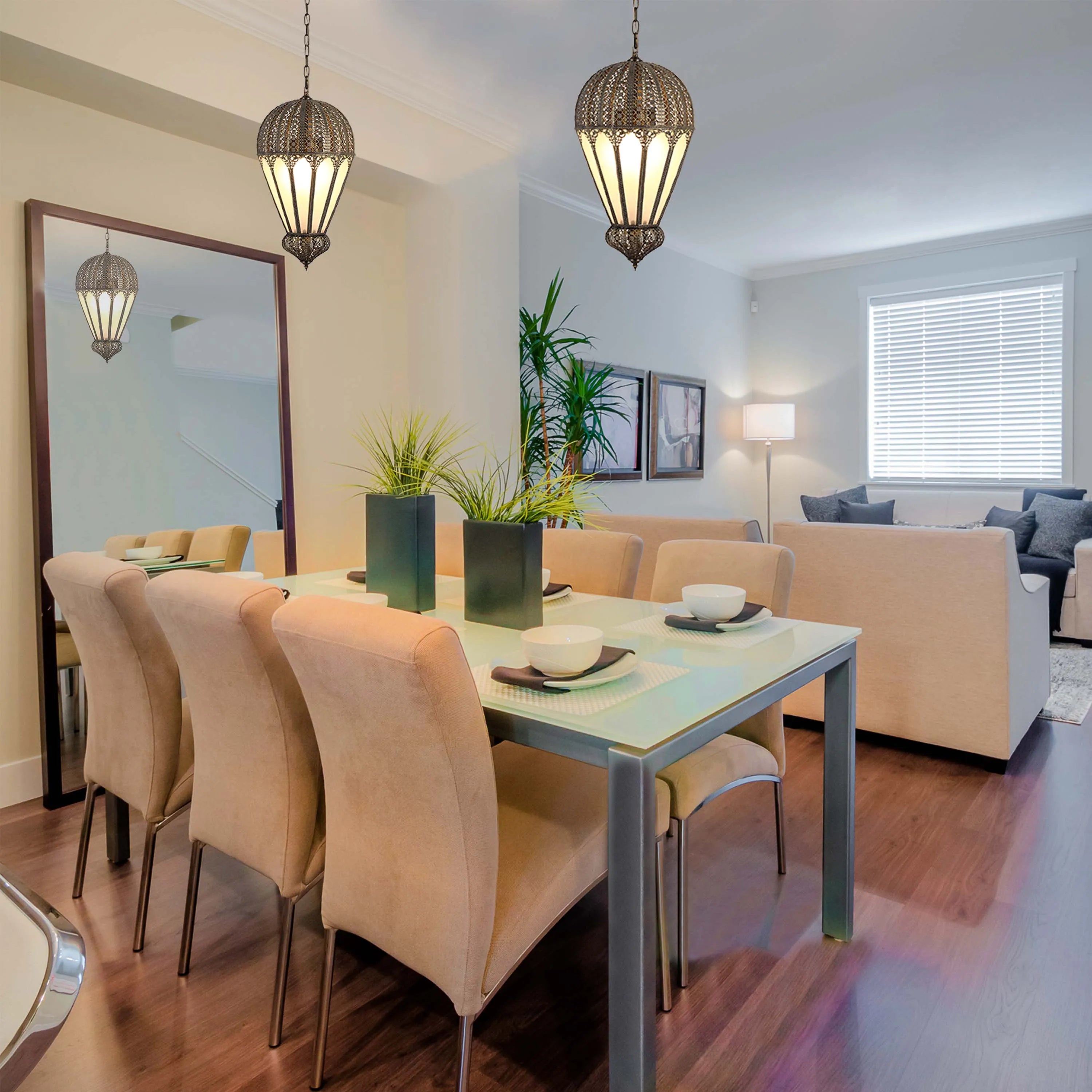 Ornate hanging lights illuminate a dining space with a modern glass table and neutral-toned chairs, creating a warm, inviting atmosphere.