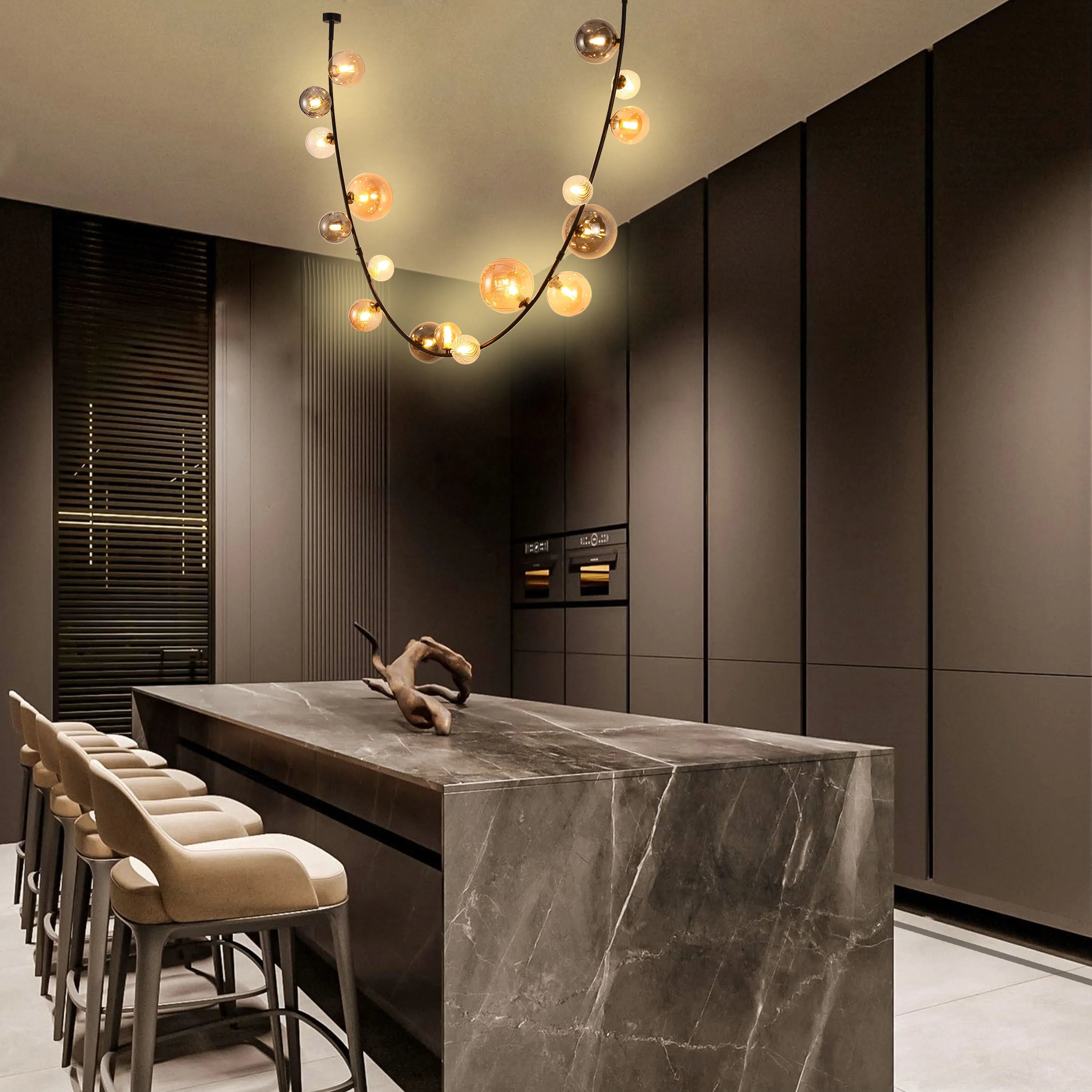 A modern kitchen featuring an eye-catching chandelier with multiple glass spheres, casting a warm, inviting glow over the marble island.