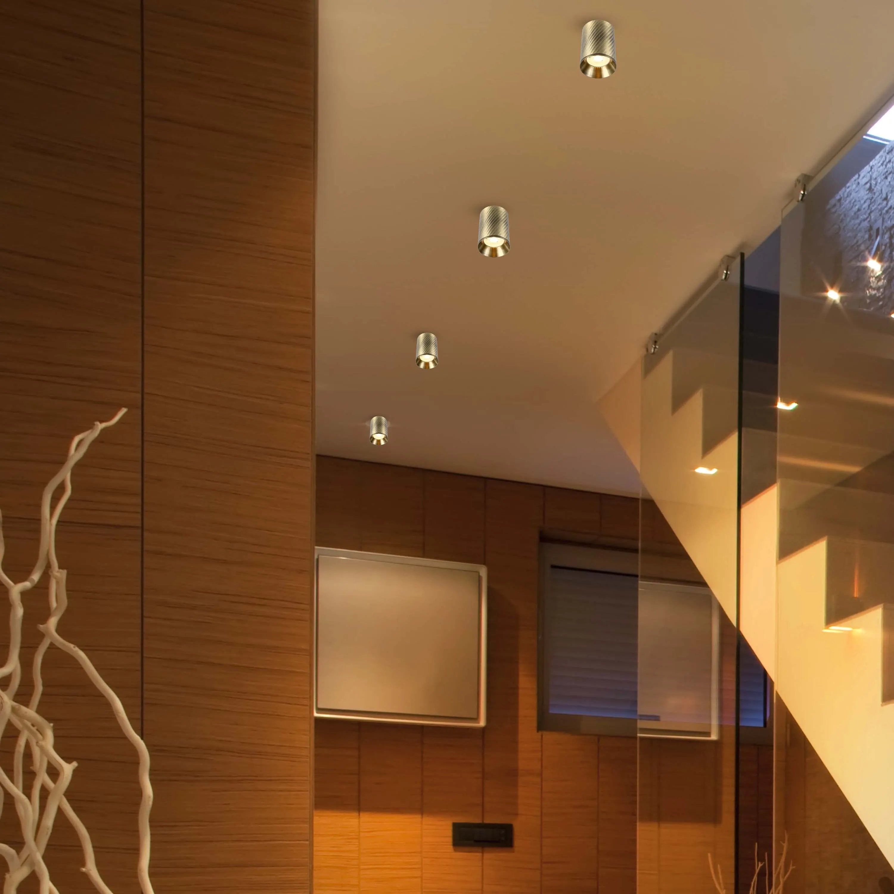Modern interior lighting design featuring four stylish, recessed ceiling lights that illuminate a staircase with glass railings.