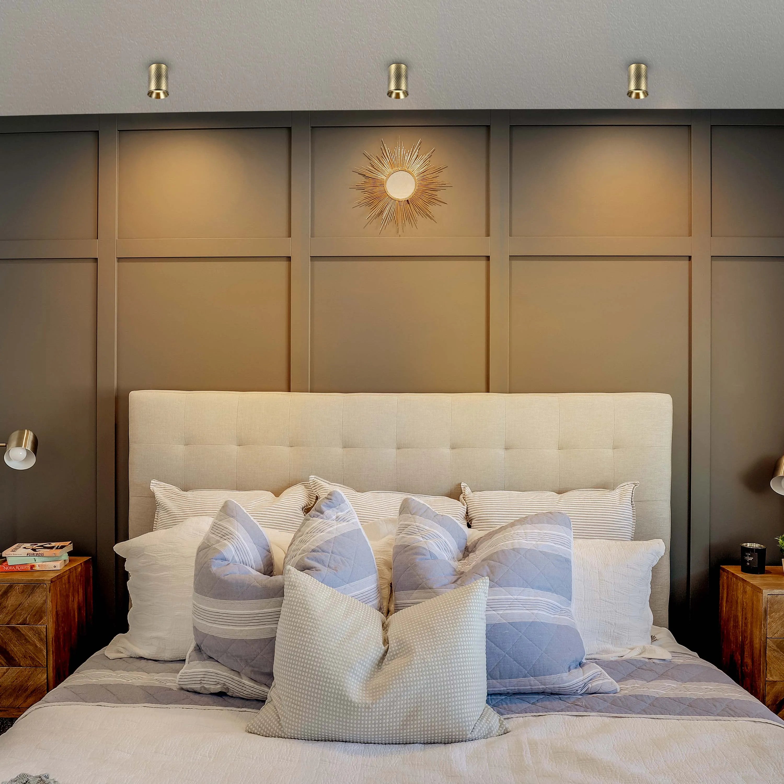 Bedroom featuring three gold-toned ceiling lights and two wall-mounted lamps, providing ambient and task lighting.