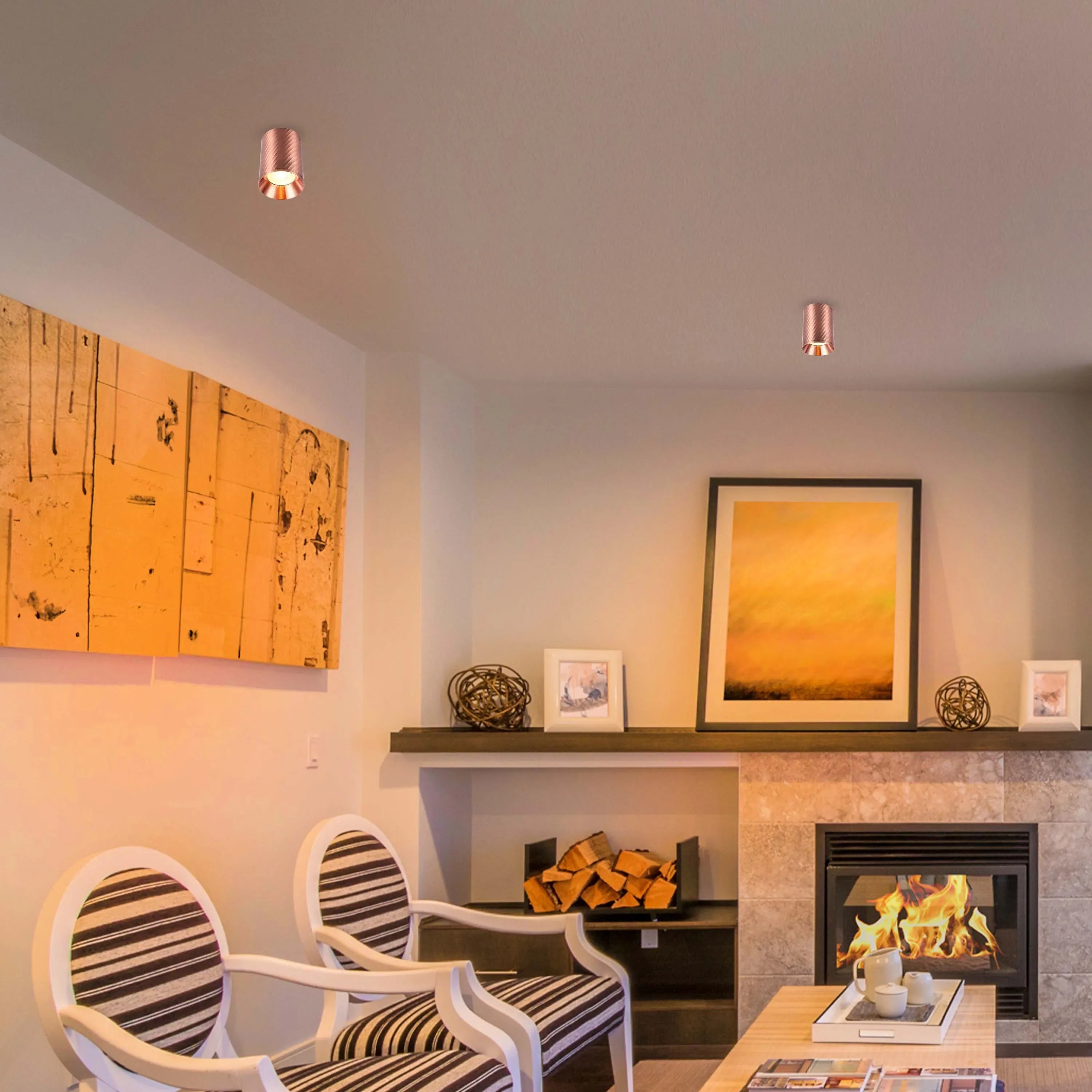 Stylish copper spotlights provide ambient lighting in this living room, illuminating the artwork and fireplace for a warm, inviting atmosphere.